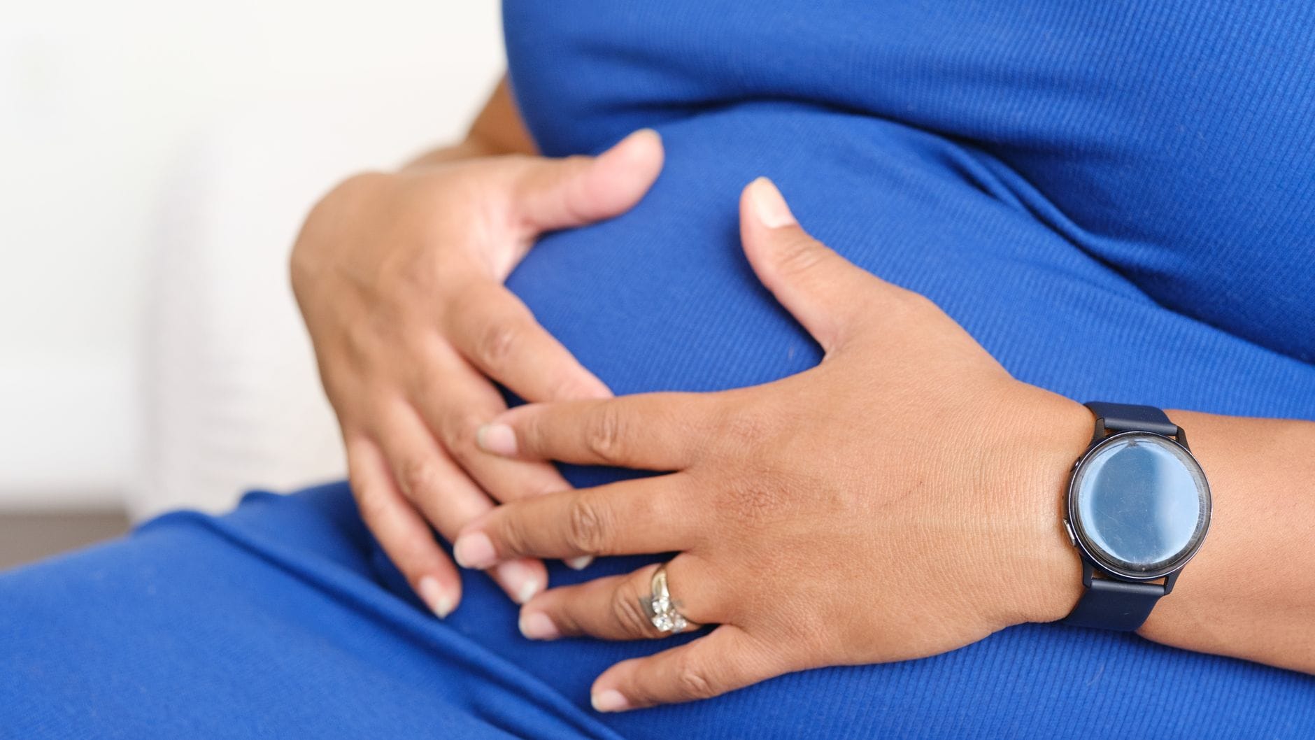 Expectant mother cradling her belly beside a sunlit window