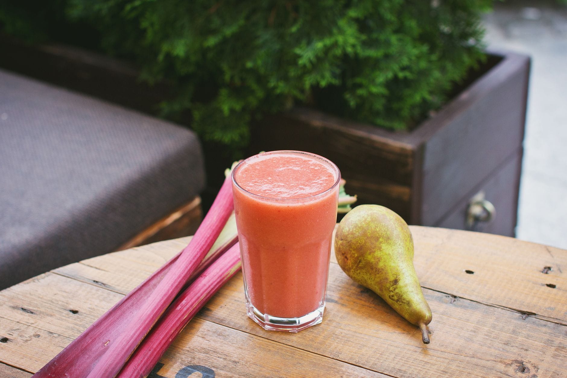 Green fruit and vegetable smoothie in a glass beside fresh produce