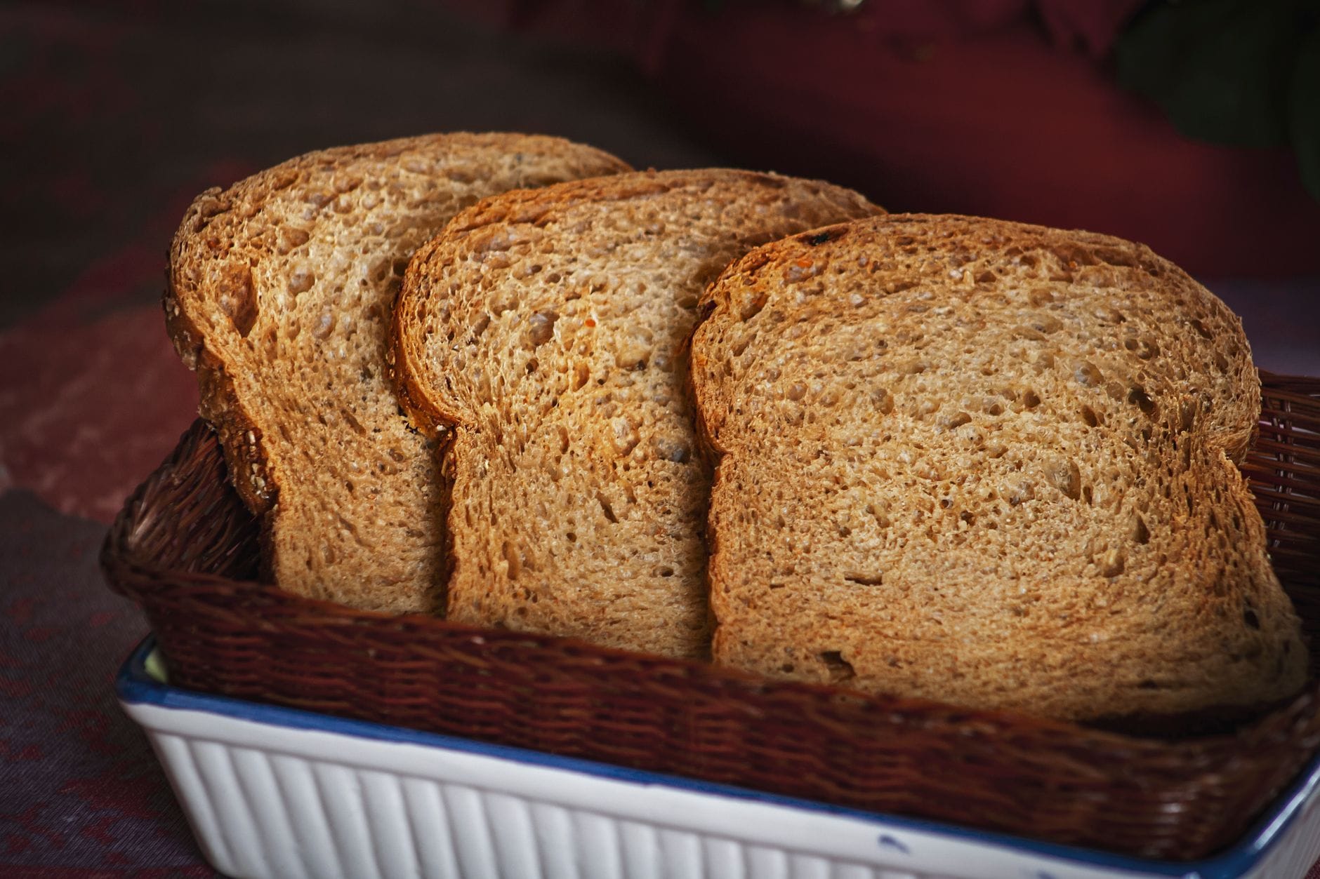 Sliced whole grain bread drizzled with golden olive oil on a wooden board