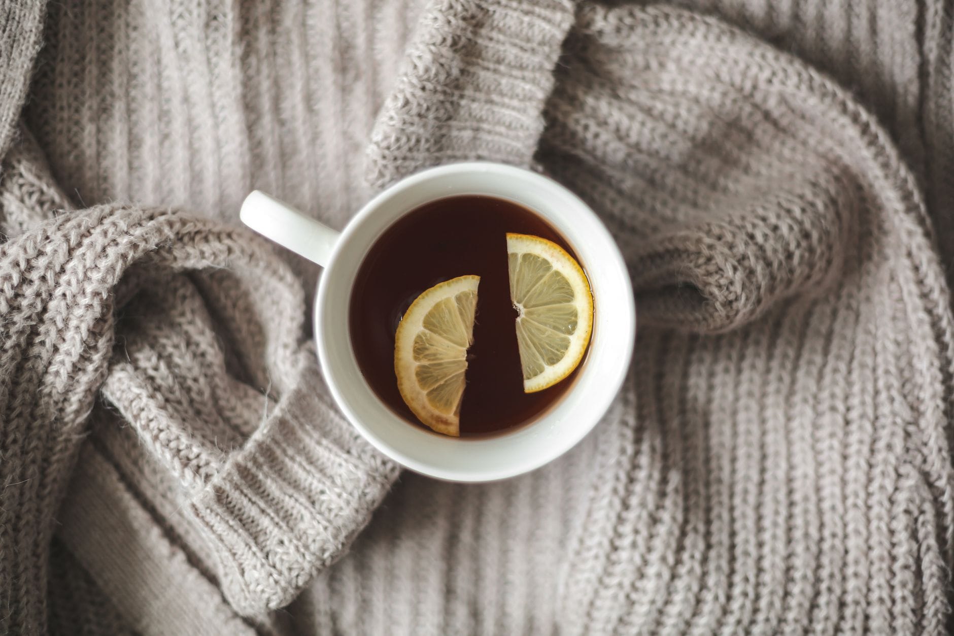 Cup of amber Earl Grey tea beside a saucer on a wooden table