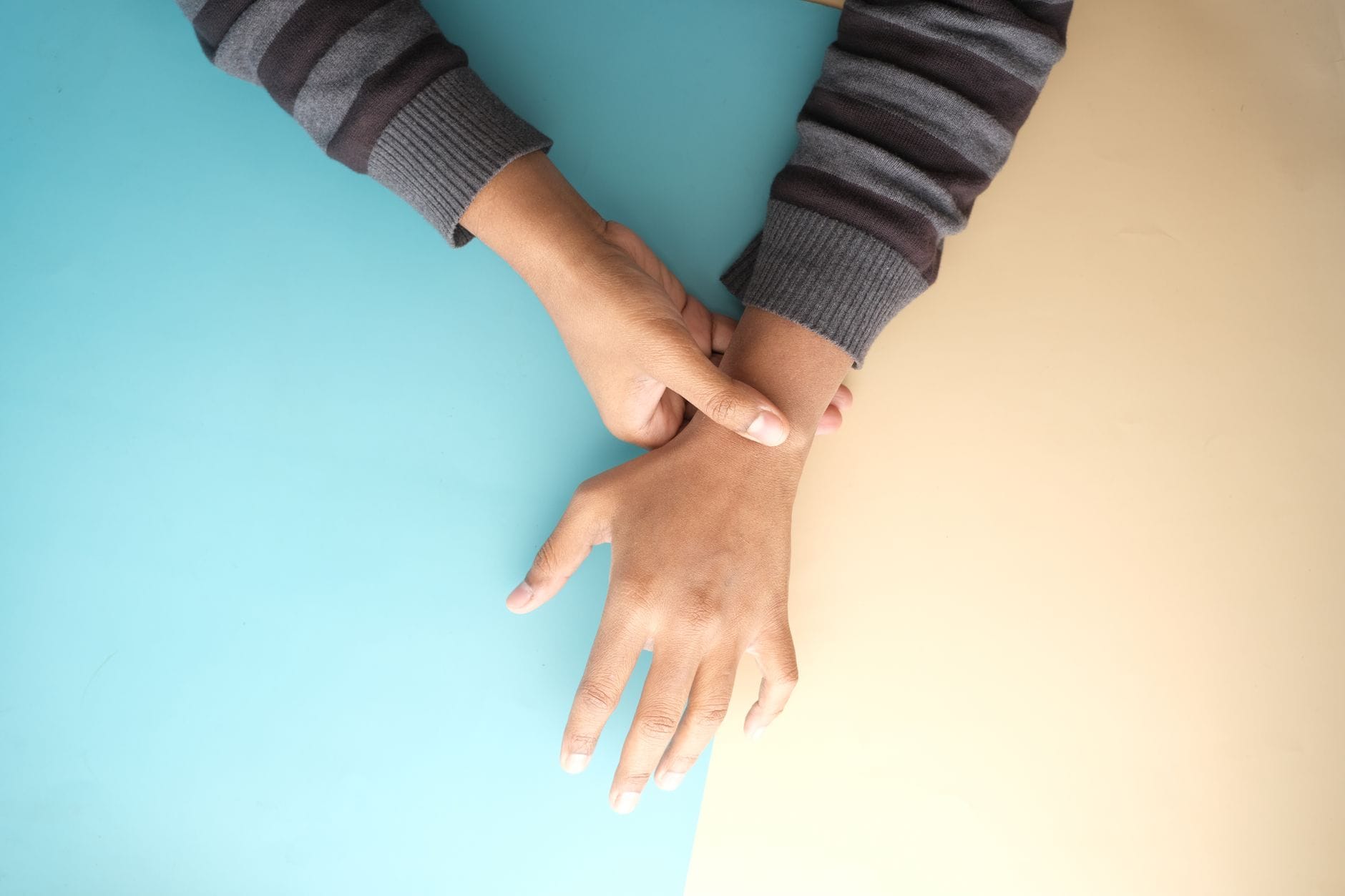 Person holding one hand over a sore wrist against a plain background