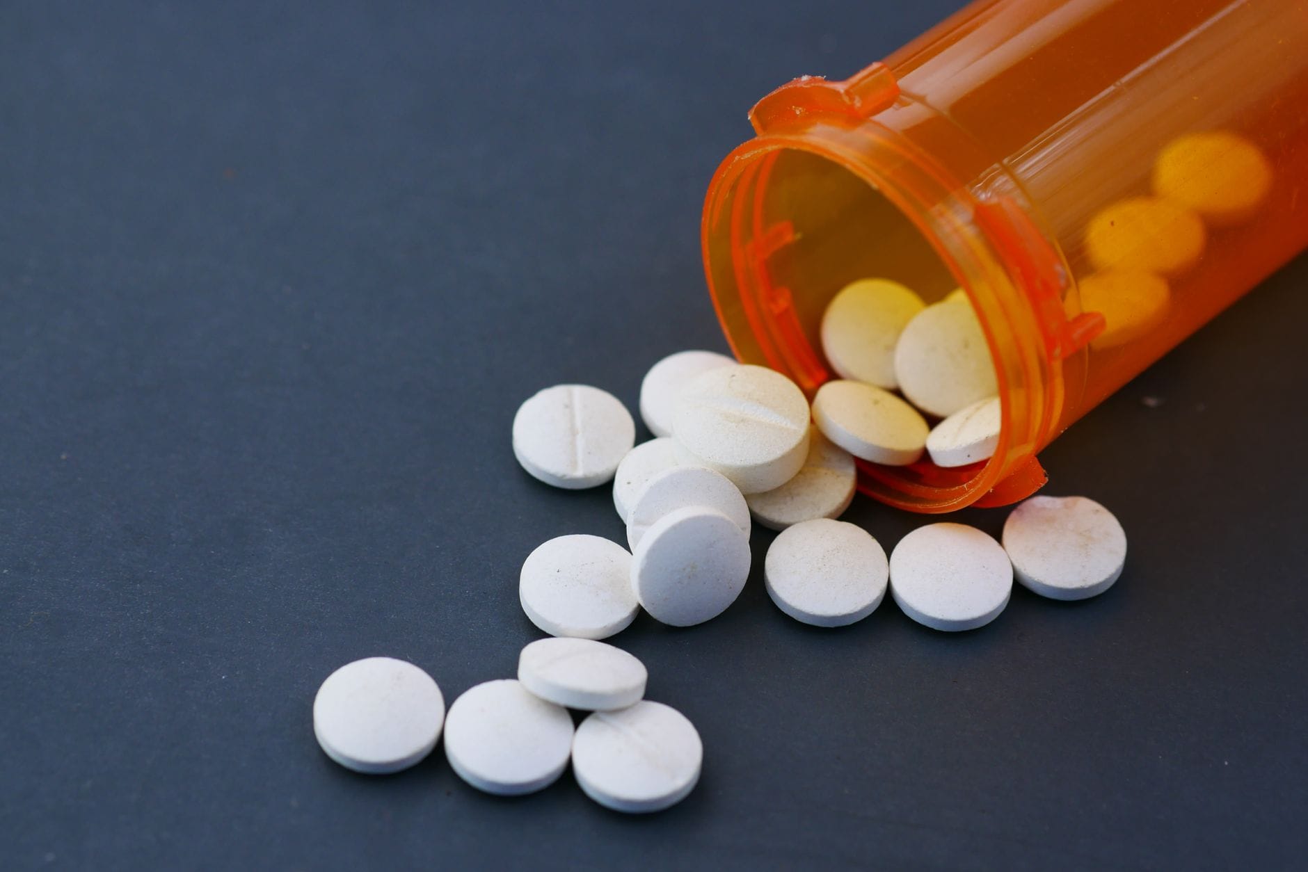 White tablets spilling from an open bottle onto a table
