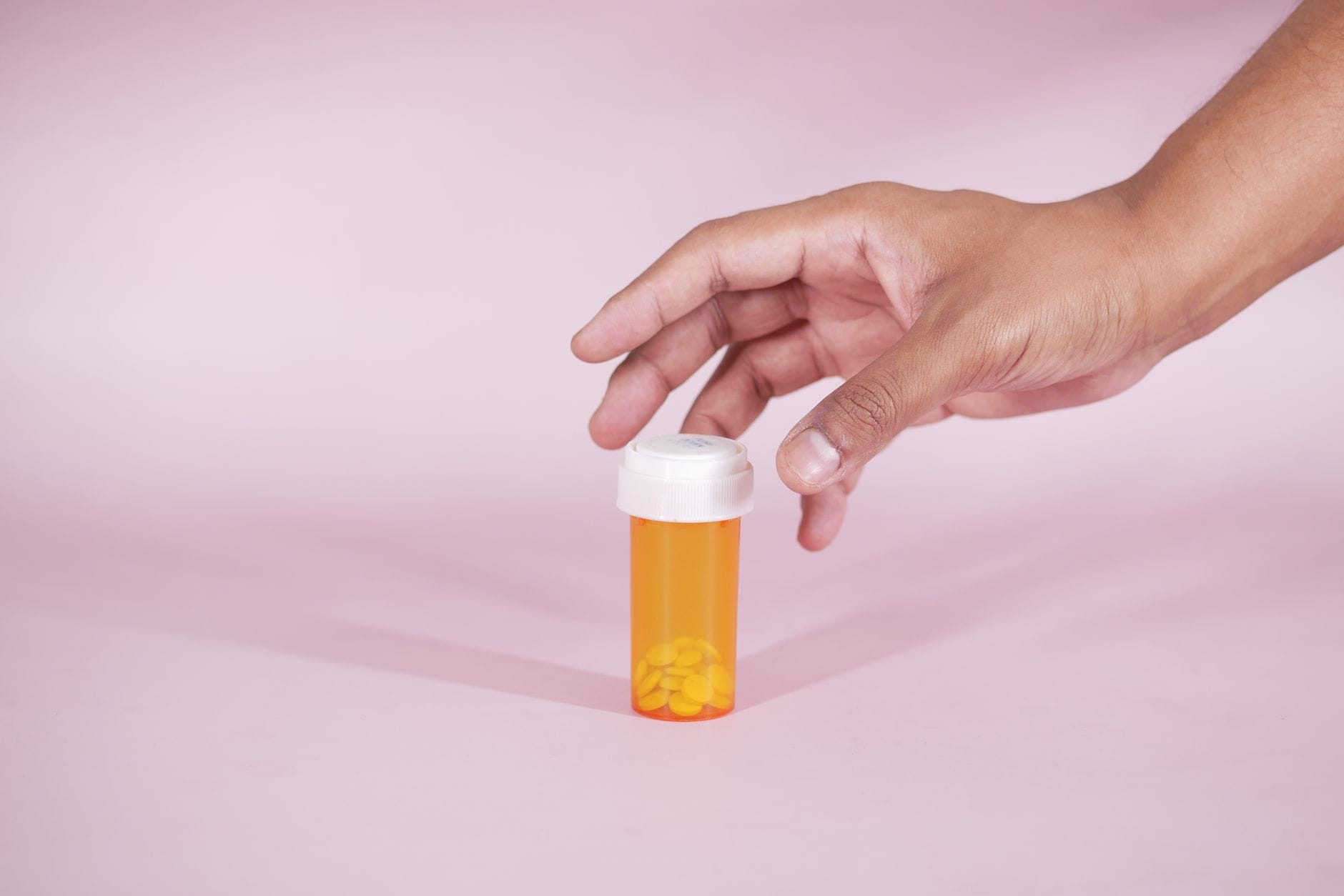 White pills spilling from an open prescription bottle on a table