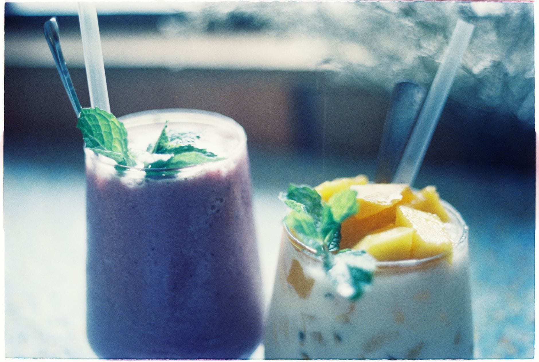 Creamy purple smoothie in a glass topped with fresh fruit