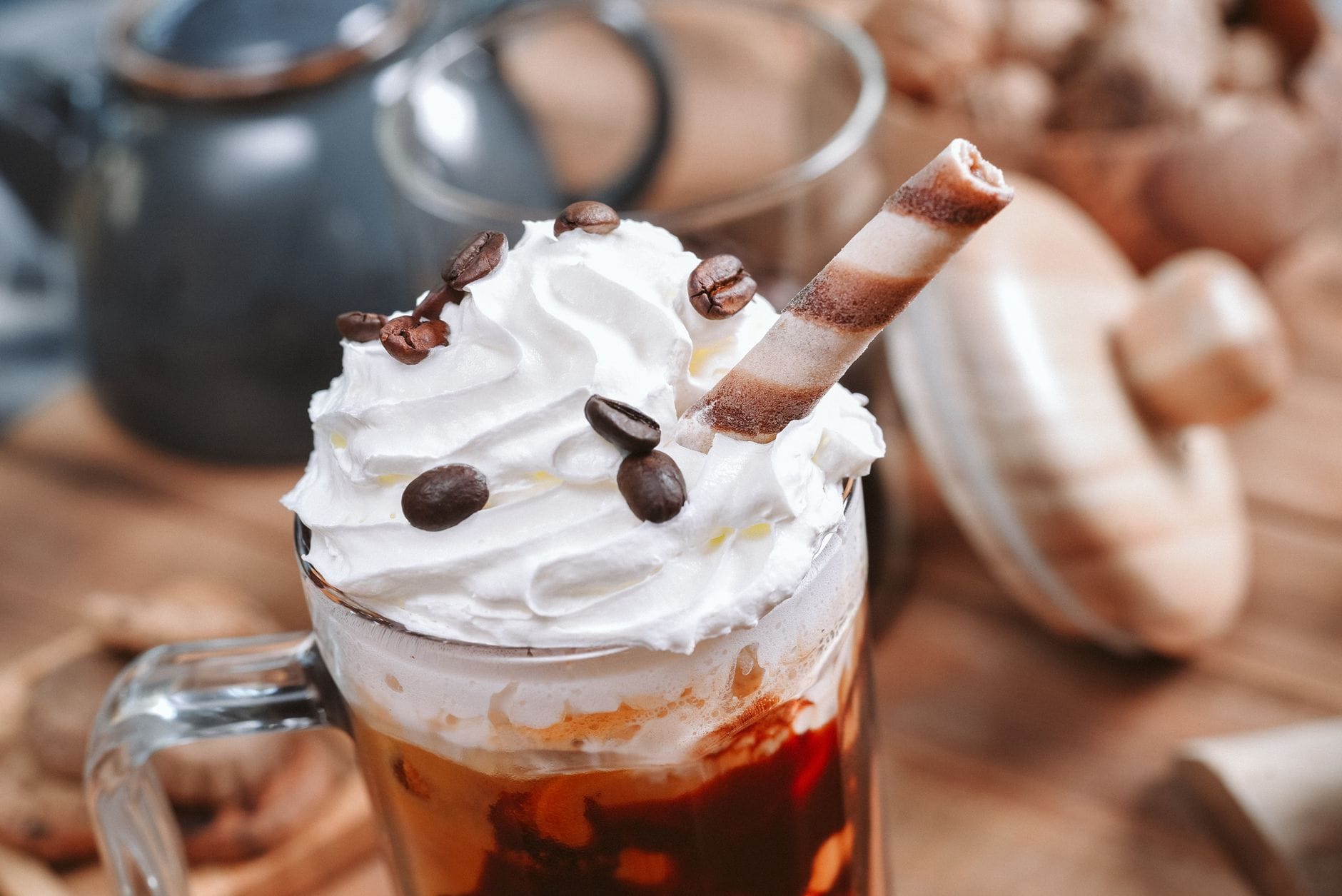 Tall glass latte topped with a swirl of whipped cream and caramel drizzle
