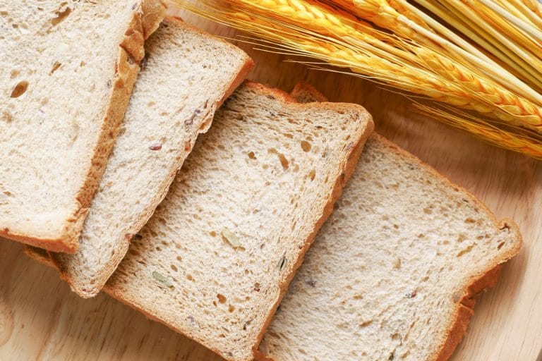 Sliced dark sprouted-grain loaf resting on a wooden board with a bread knife
