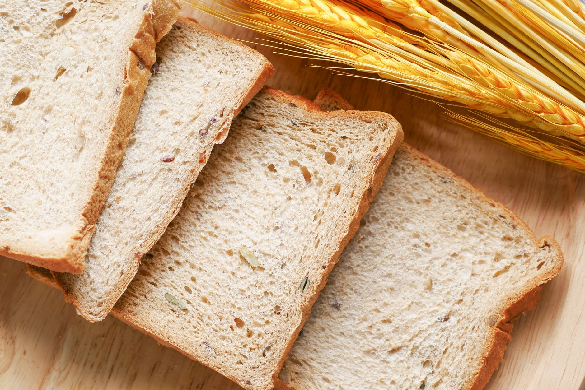 Sliced dark sprouted-grain loaf resting on a wooden board with a bread knife