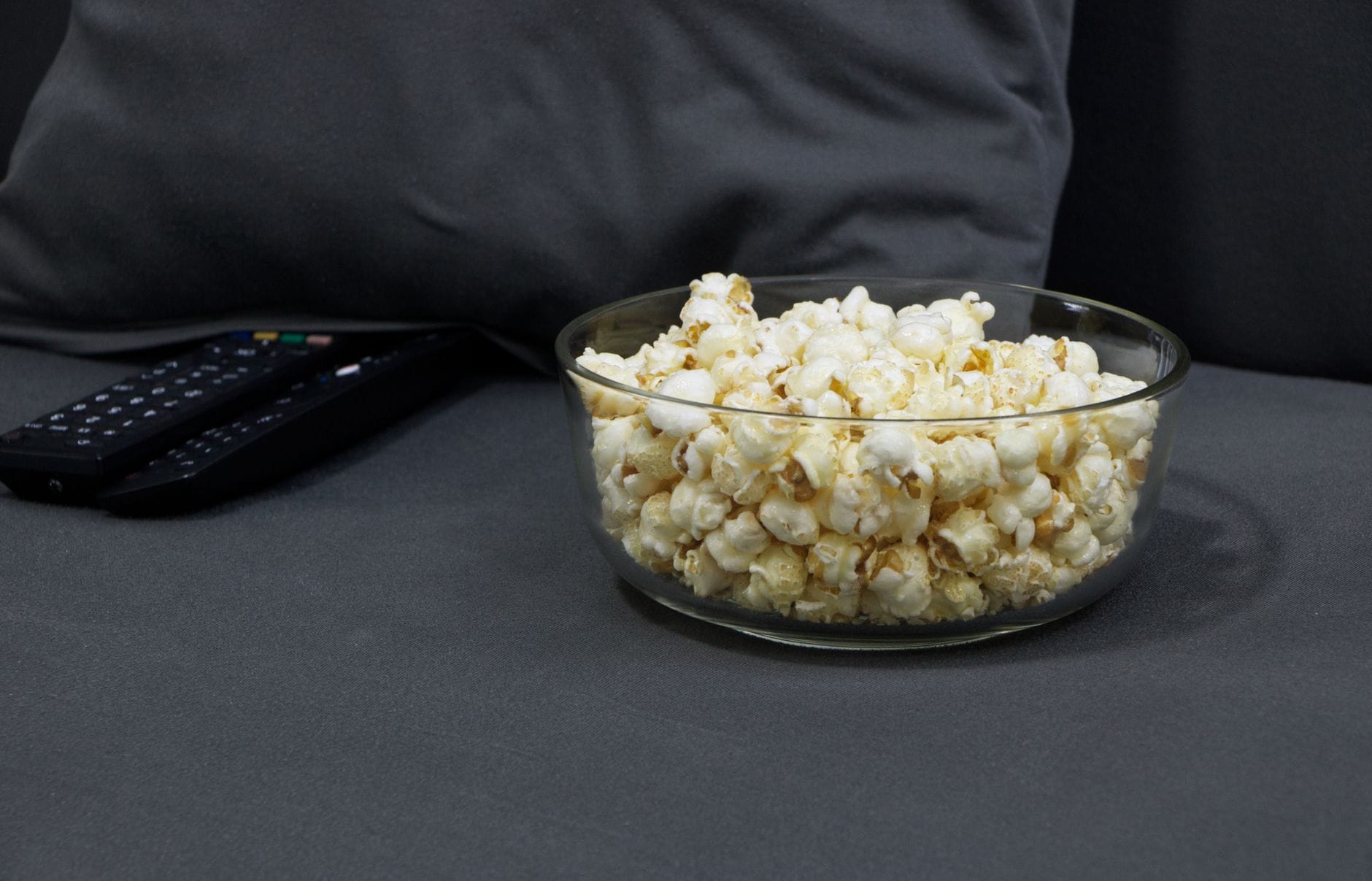 Freshly popped popcorn overflowing from a white ceramic bowl on a wooden table
