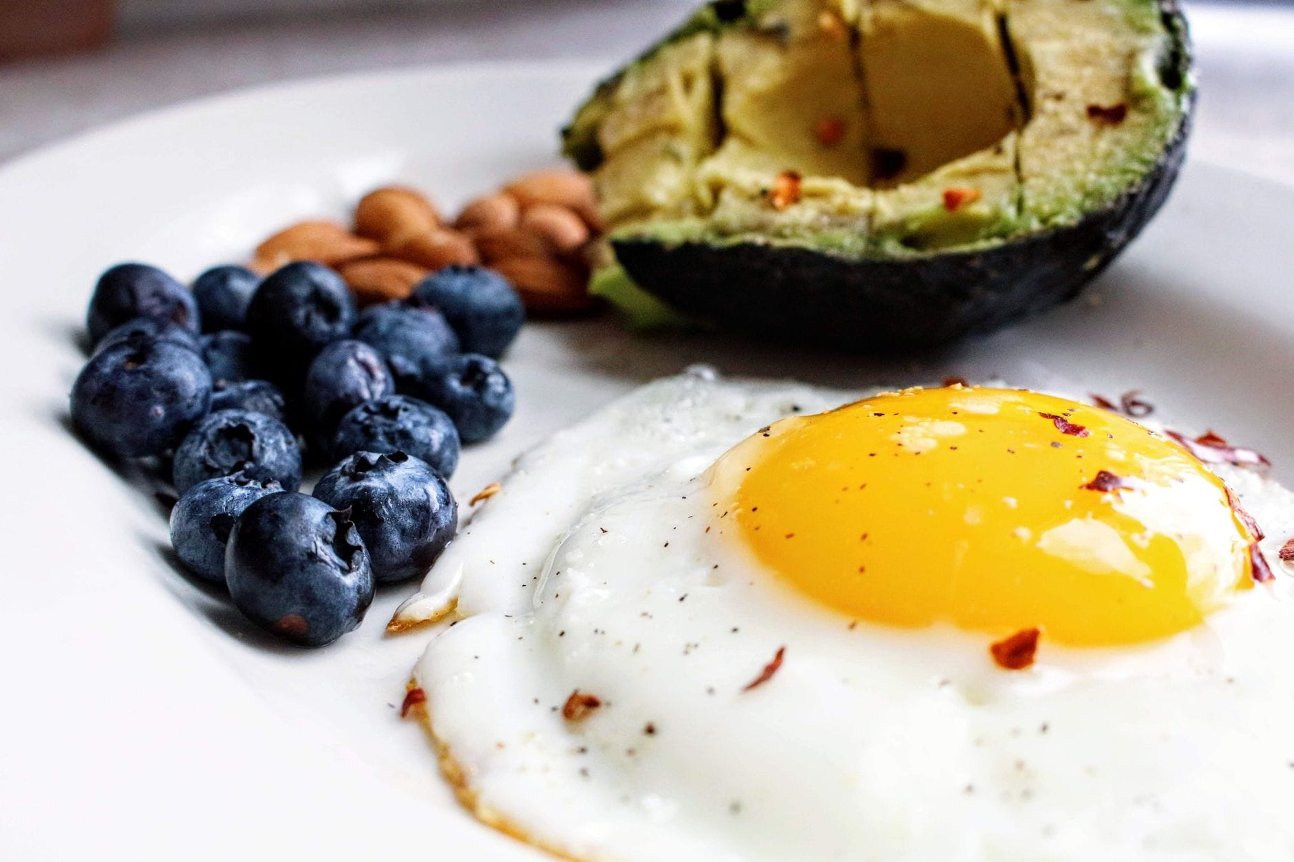 A plate of sliced avocado and fried eggs on a wooden table