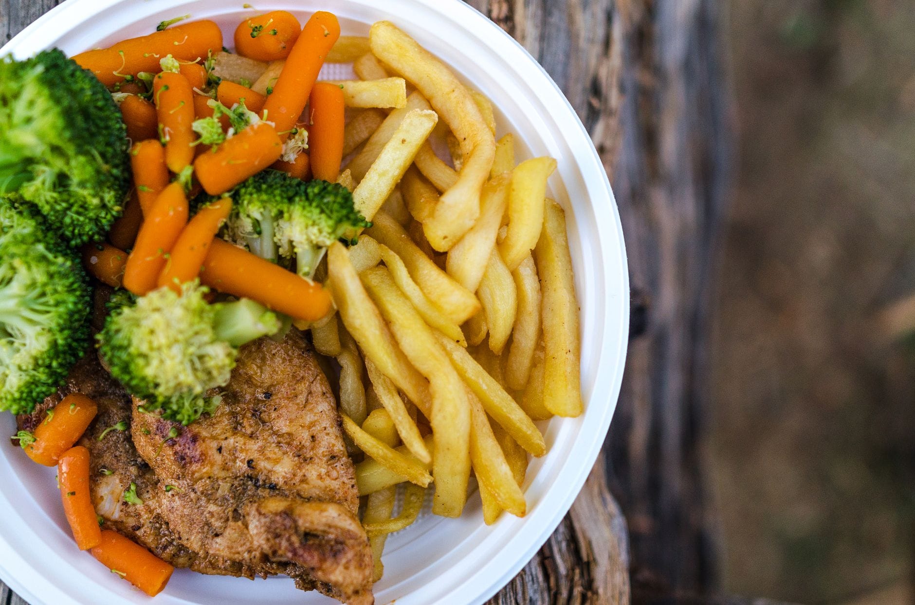 A plate of grilled chicken, brown rice, and steamed vegetables on a table