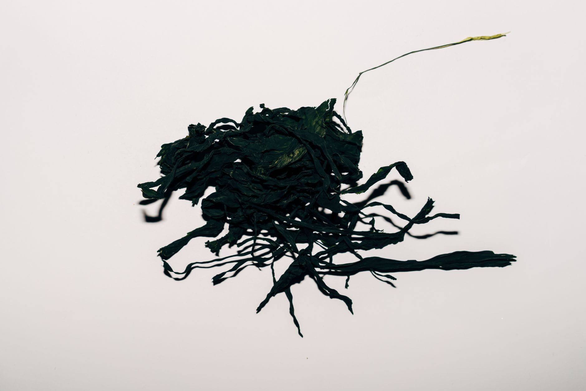 Folded sheets of dried kombu kelp stacked on a wooden board