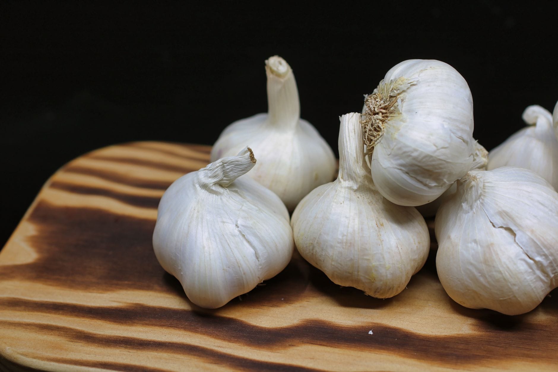 Dark sticky peeled black garlic cloves resting on a slate plate