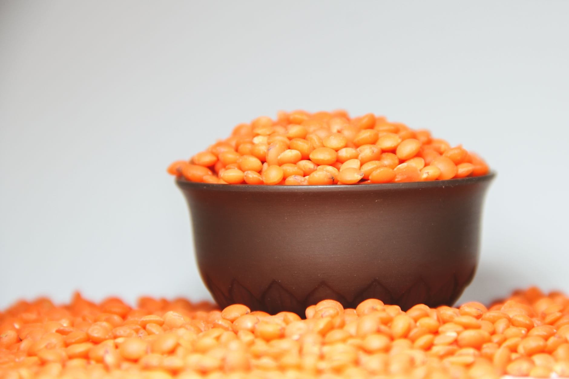 Cooked brown lentils piled high in a white ceramic bowl