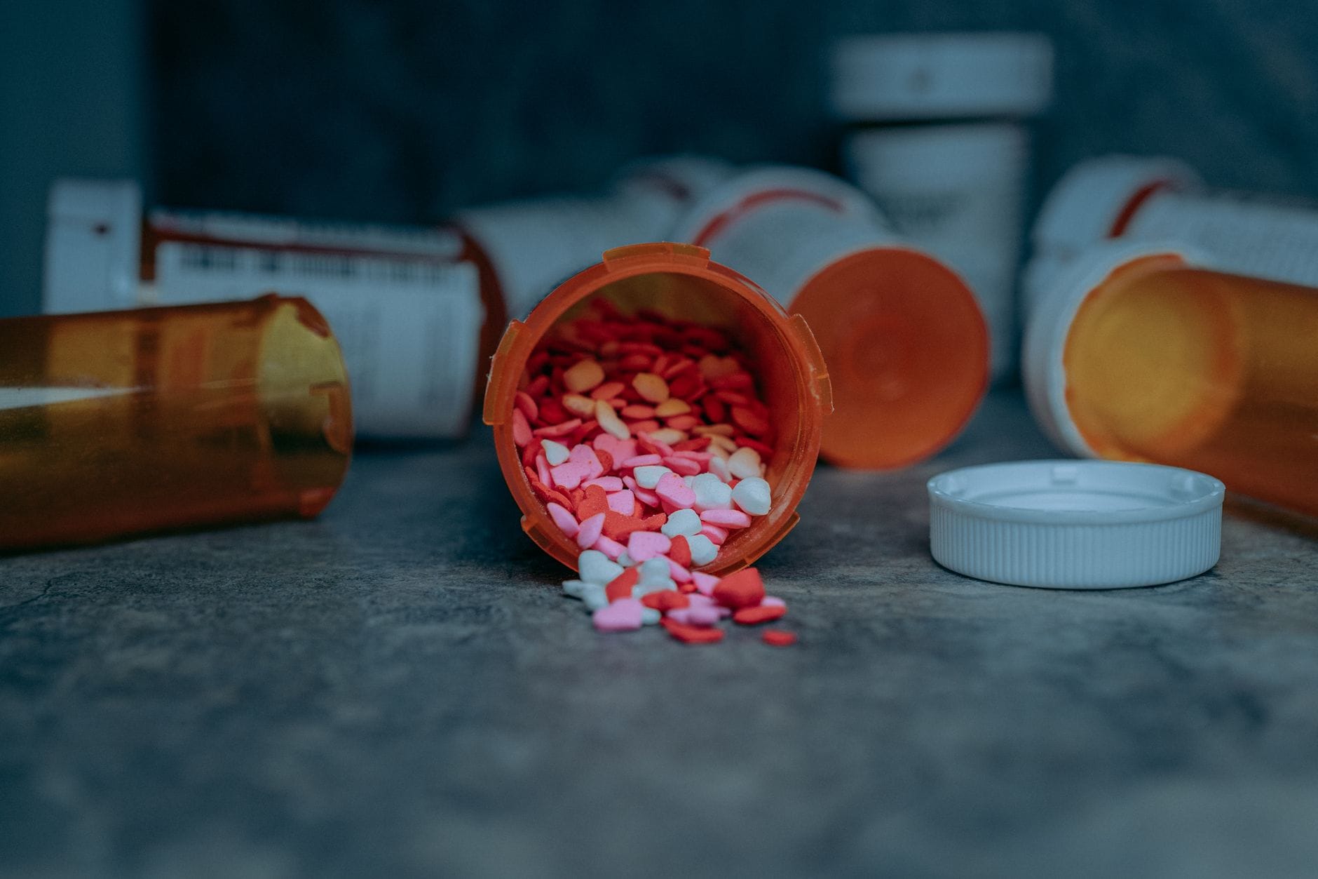 Several open prescription medication bottles with loose white pills spilling out