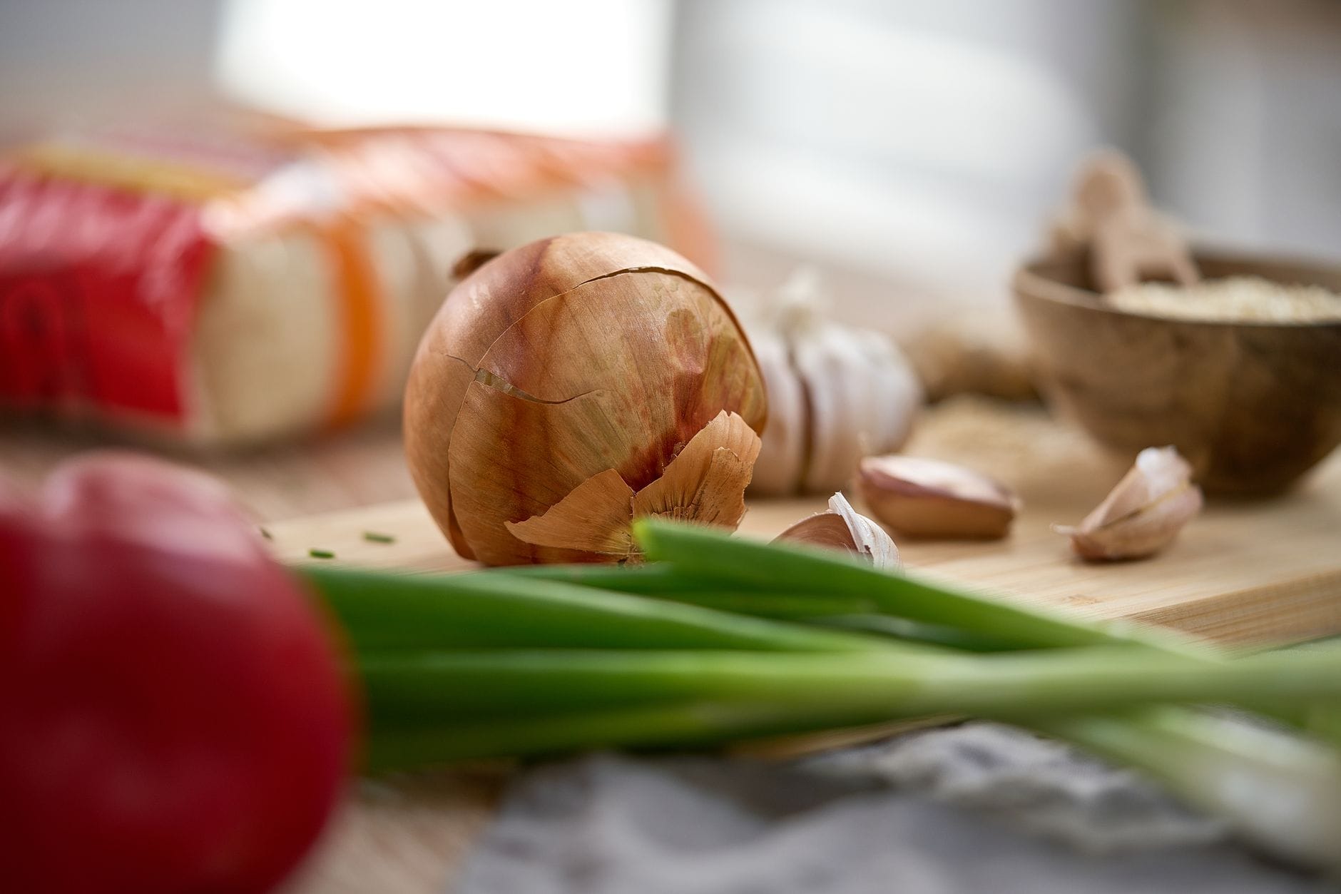 close-up of whole garlic bulbs and red onions on a wooden board