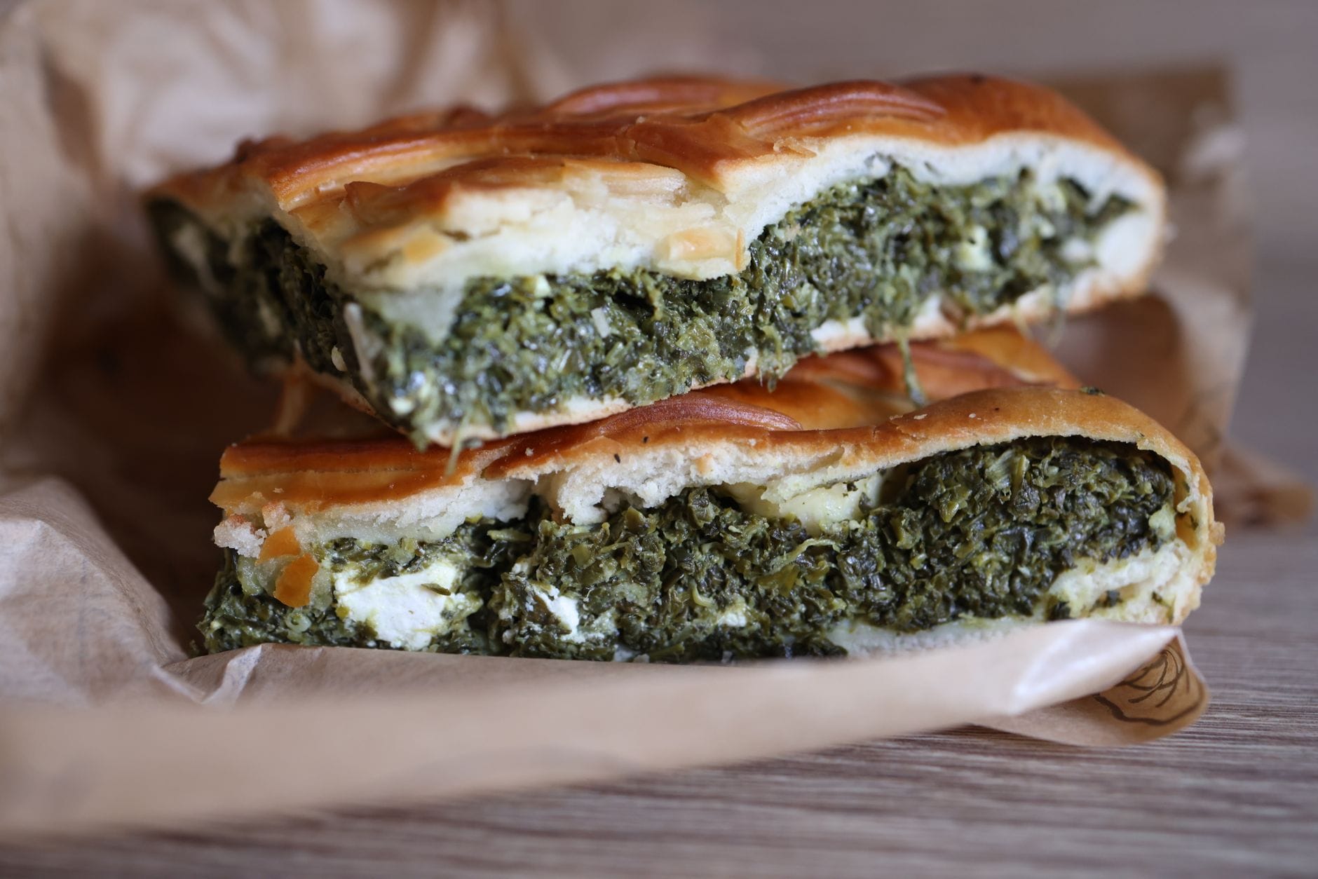 Chopped spinach and crumbled feta cheese in bowls on a wooden board