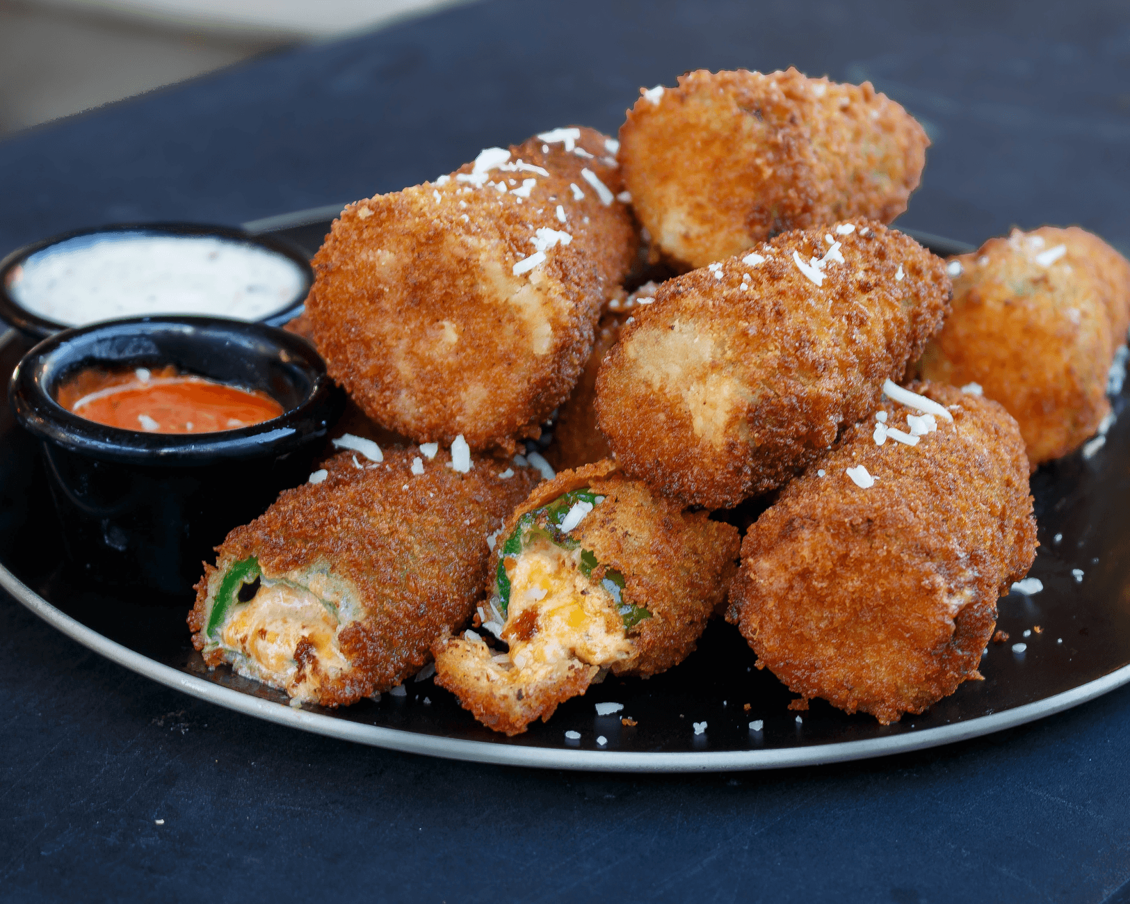 Breaded jalapeño poppers filled with melted cheese on a white plate