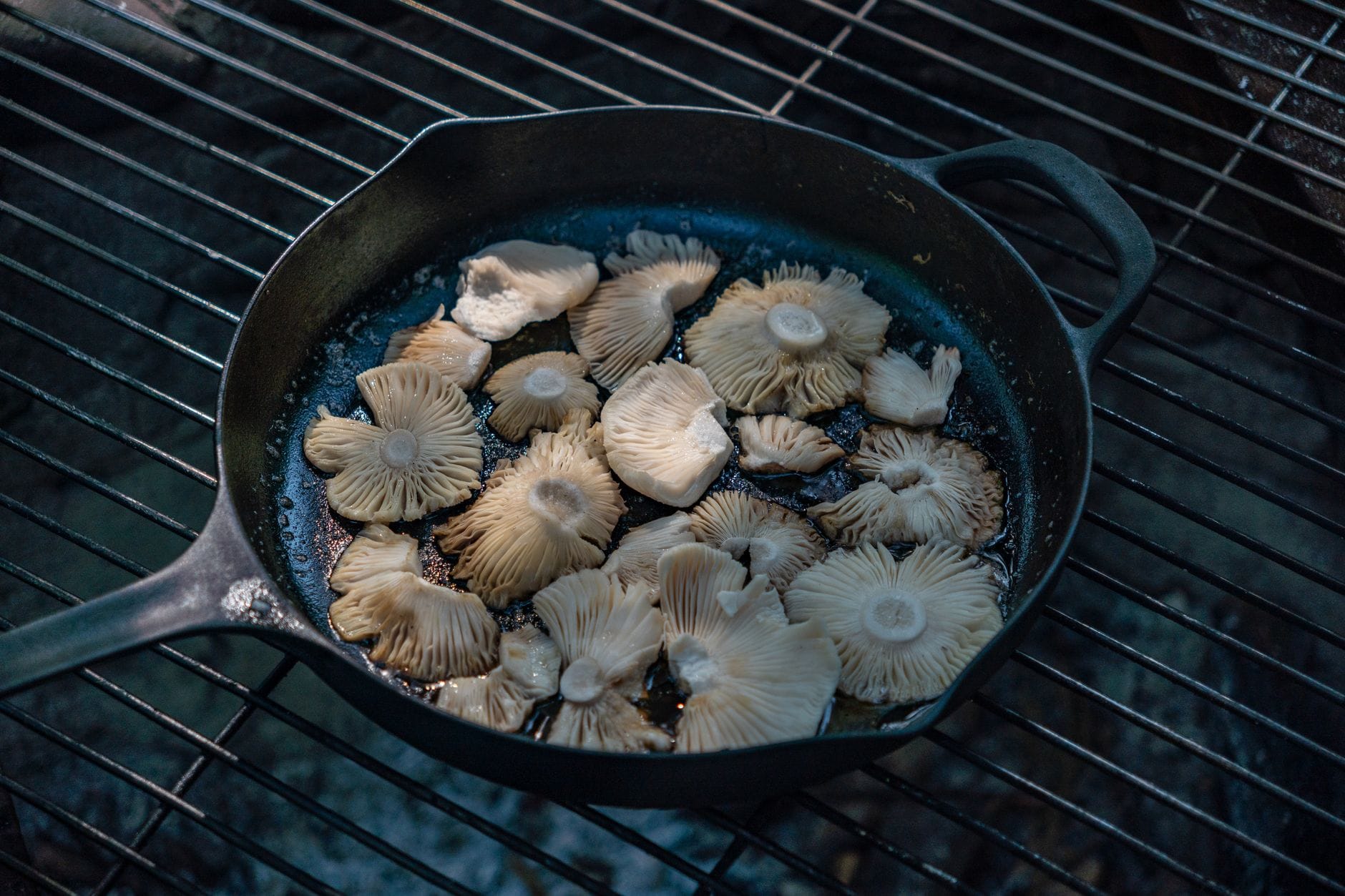 Sliced sunchokes sizzling in a cast iron skillet with herbs