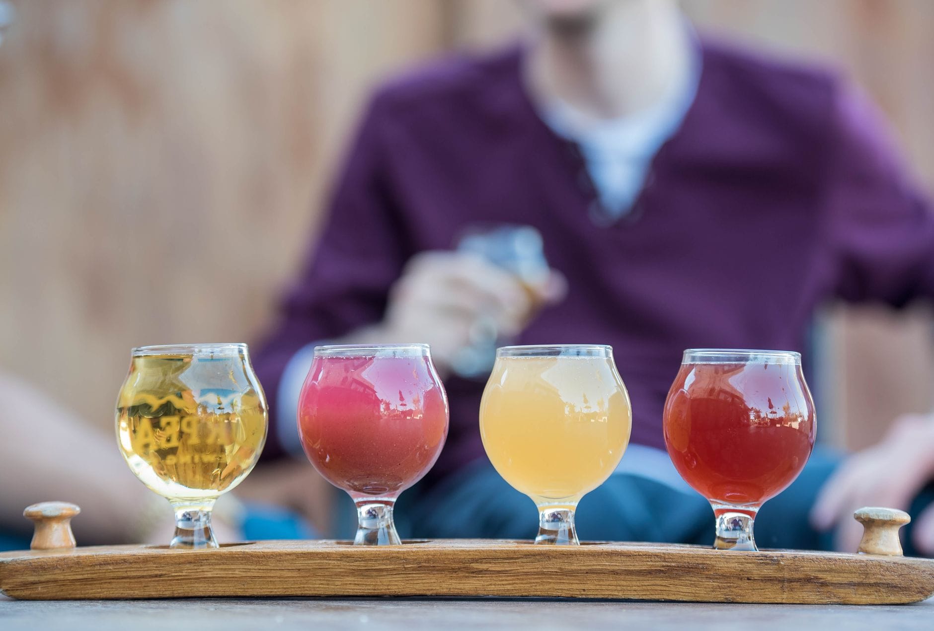Row of small tasting glasses filled with different colored beers