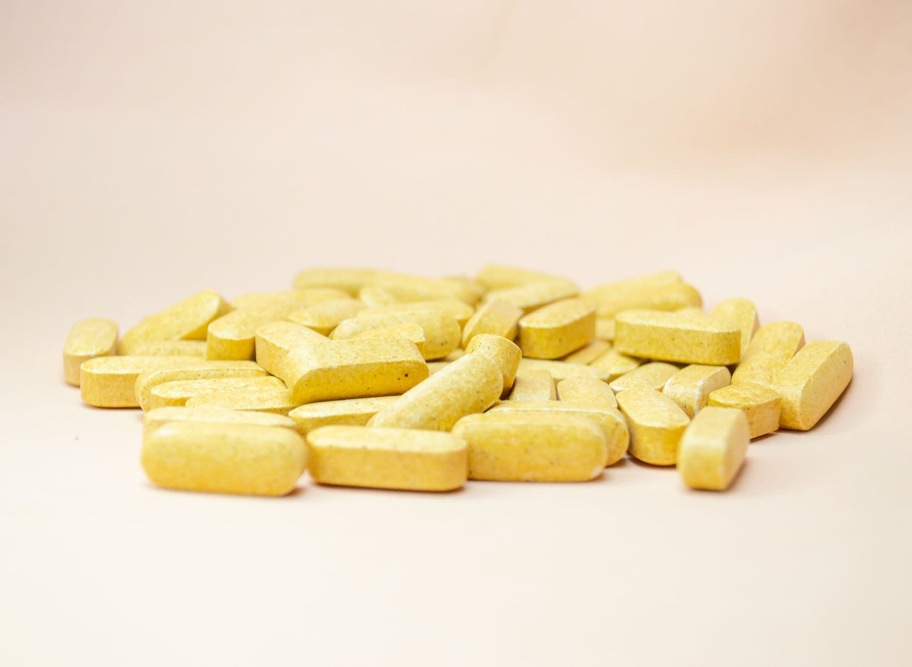 Orange vitamin tablets spilling from an open supplement bottle