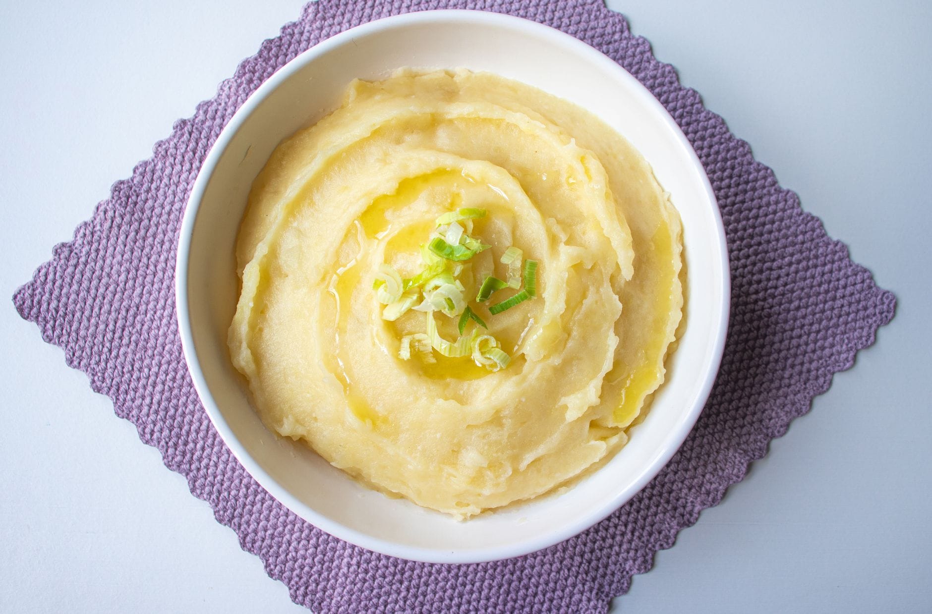 A creamy scoop of smooth mashed potatoes in a white bowl