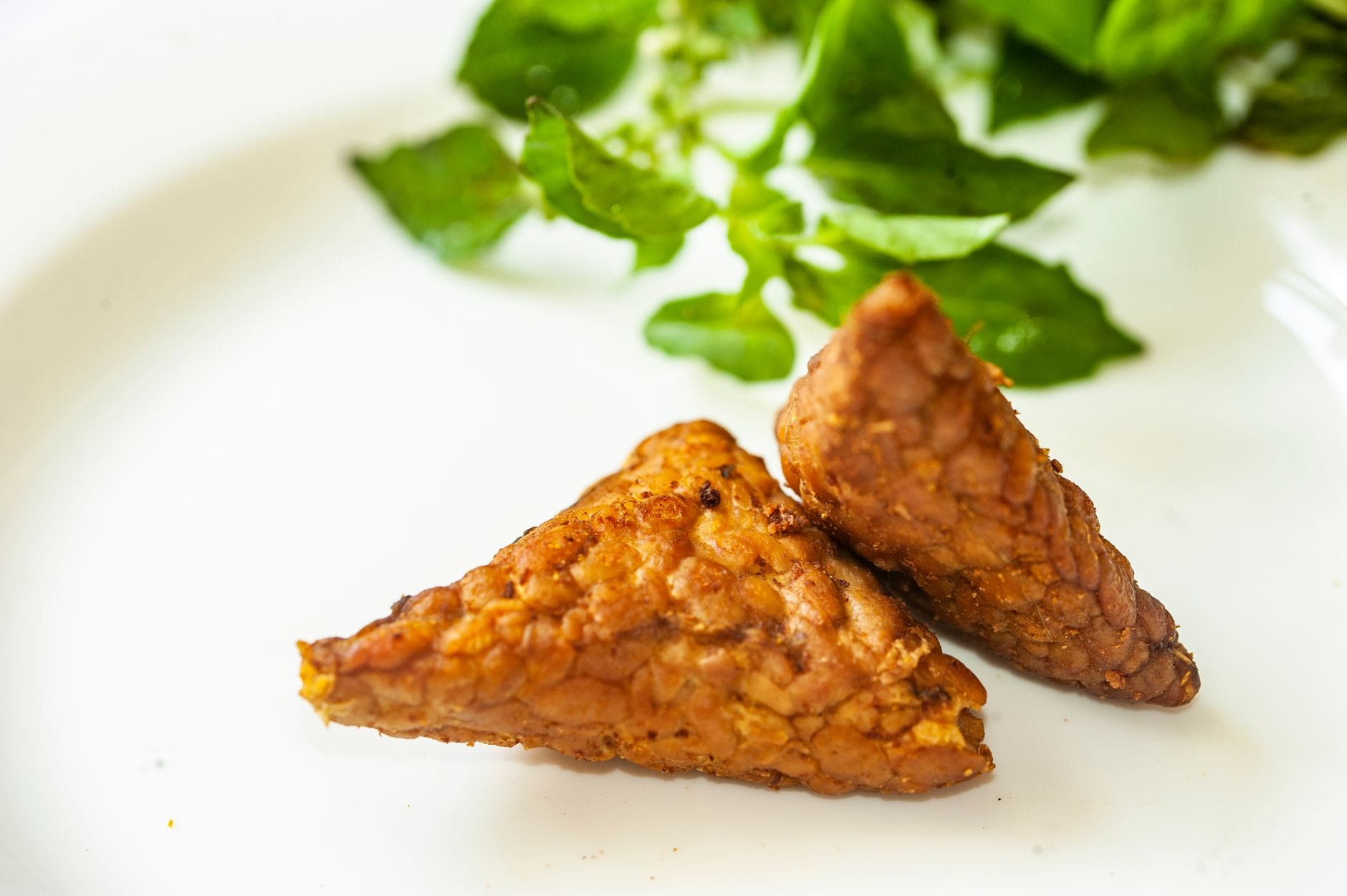 Cubed tempeh next to a small dish of soybeans on a marble counter