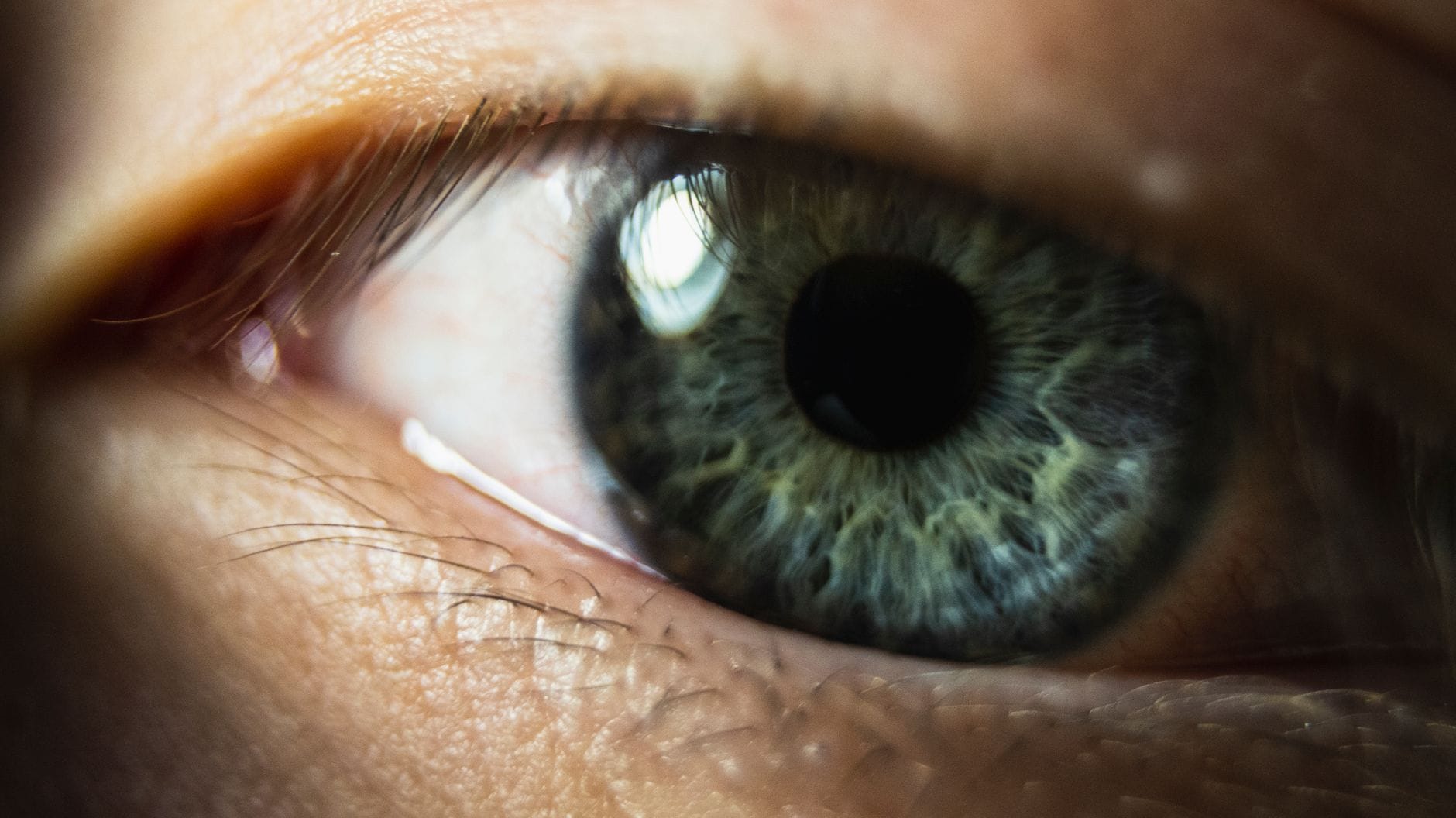 A close-up of a woman's bright blue eye and lashes