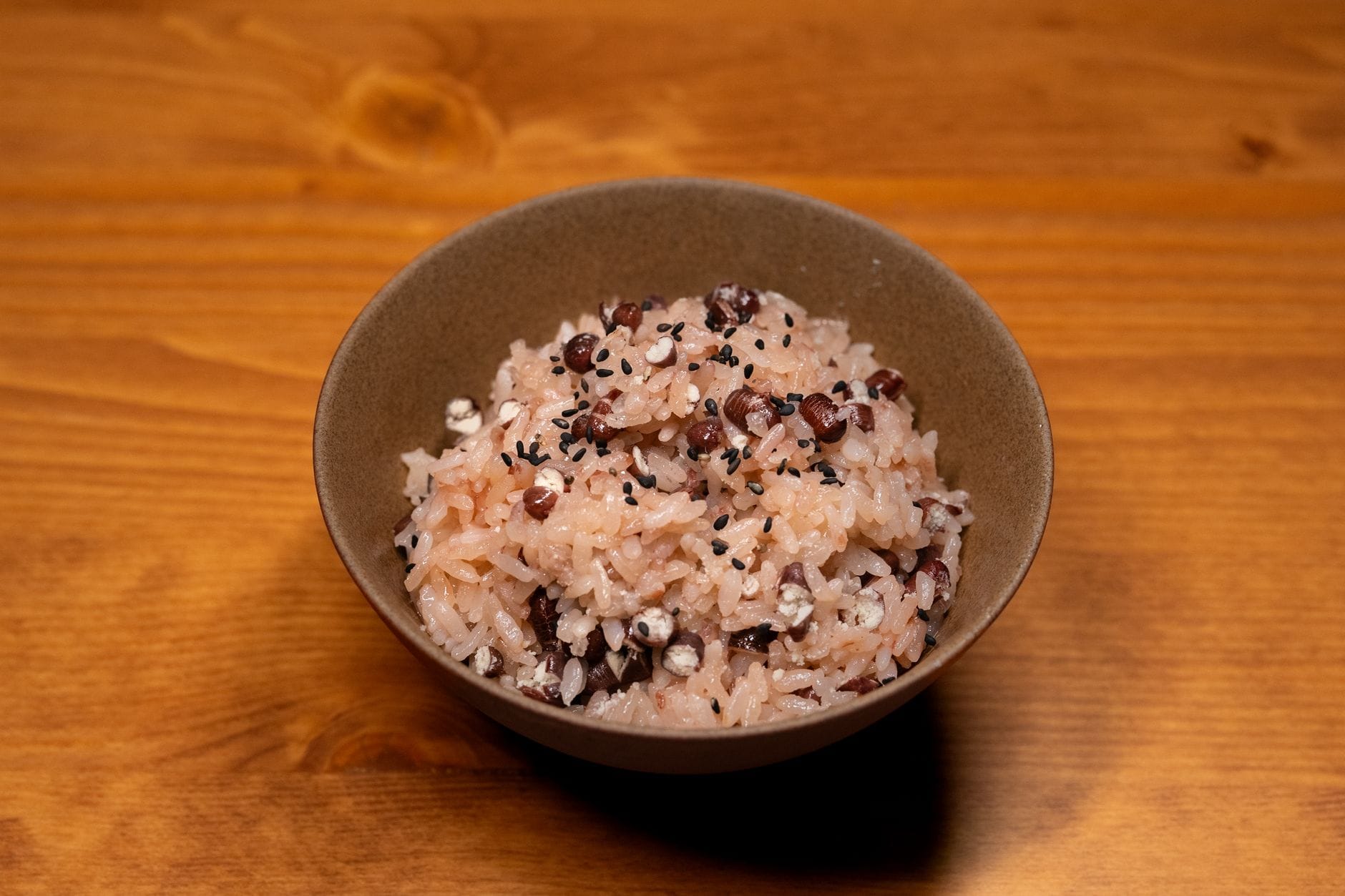 Steaming cooked brown rice served in a white ceramic bowl with chopsticks resting on the rim