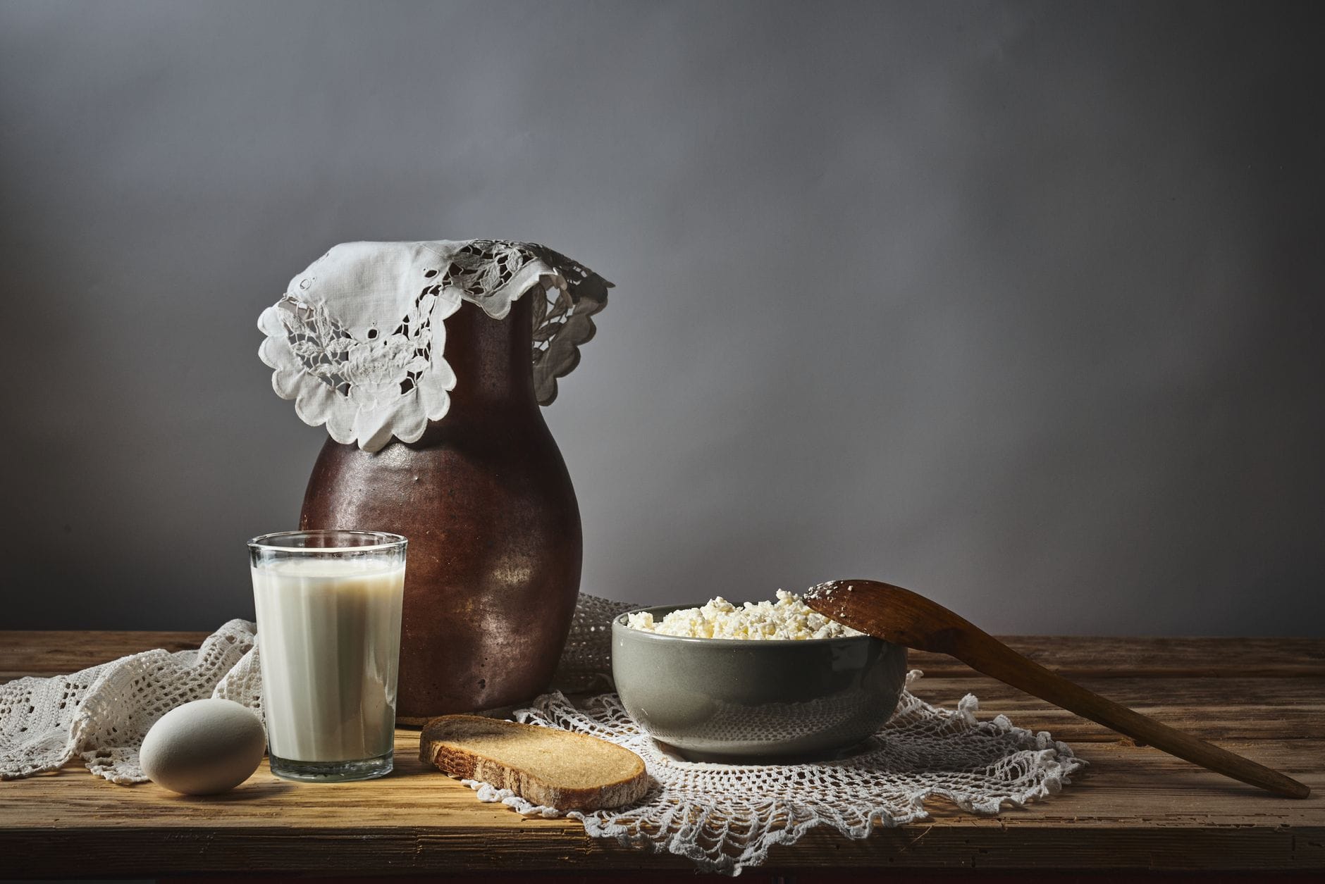 Fresh milk in a glass beside sliced cheese and yogurt