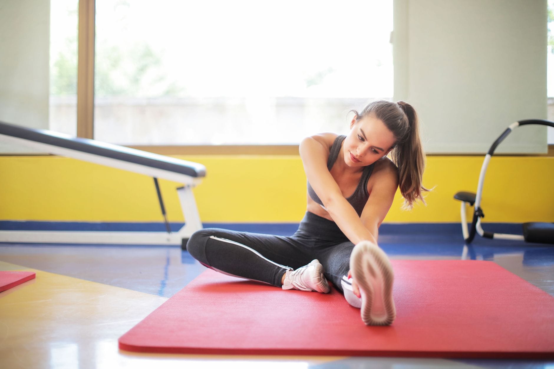 A woman in workout clothes stretching on a yoga mat indoors