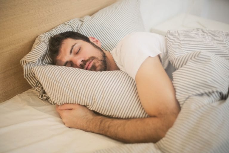 A man asleep on his back in bed with his mouth slightly open