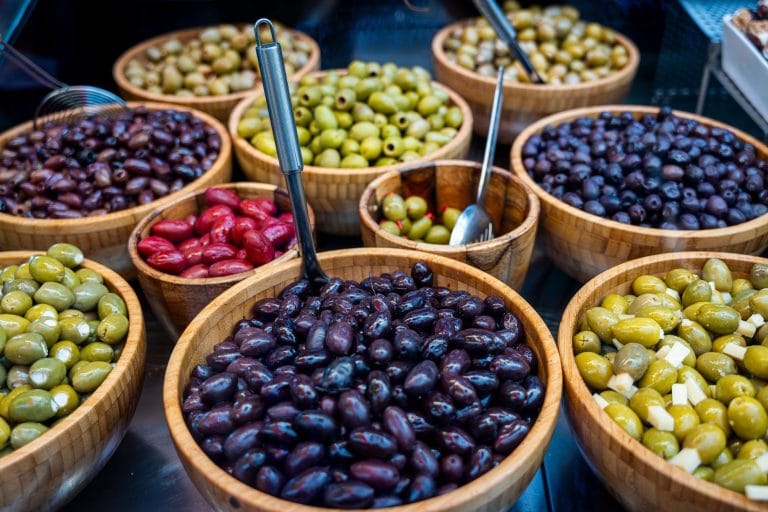 Dark purple Kalamata olives piled in a small white ceramic bowl