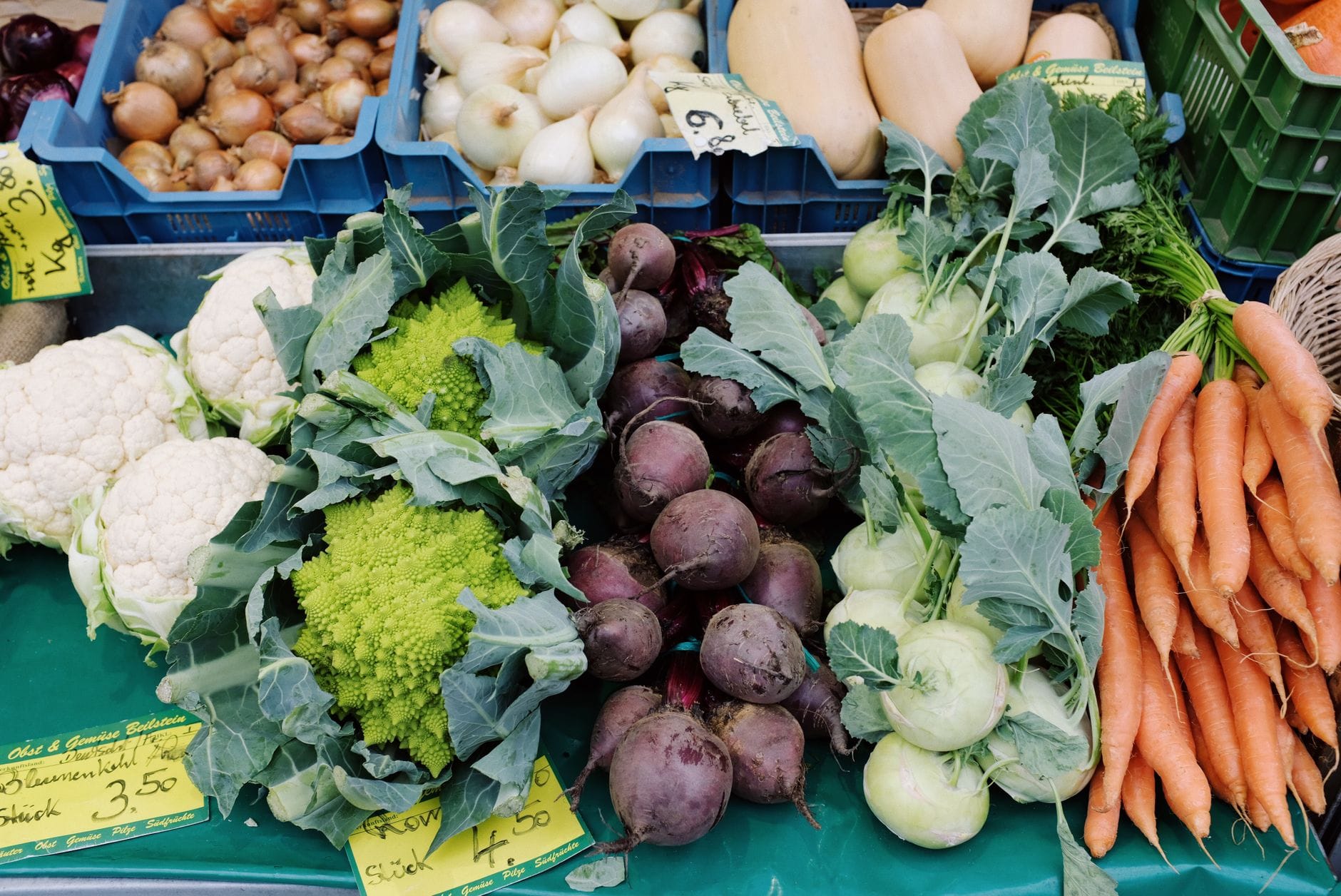 A rustic basket of unpeeled root vegetables resting on a wooden farmhouse table
