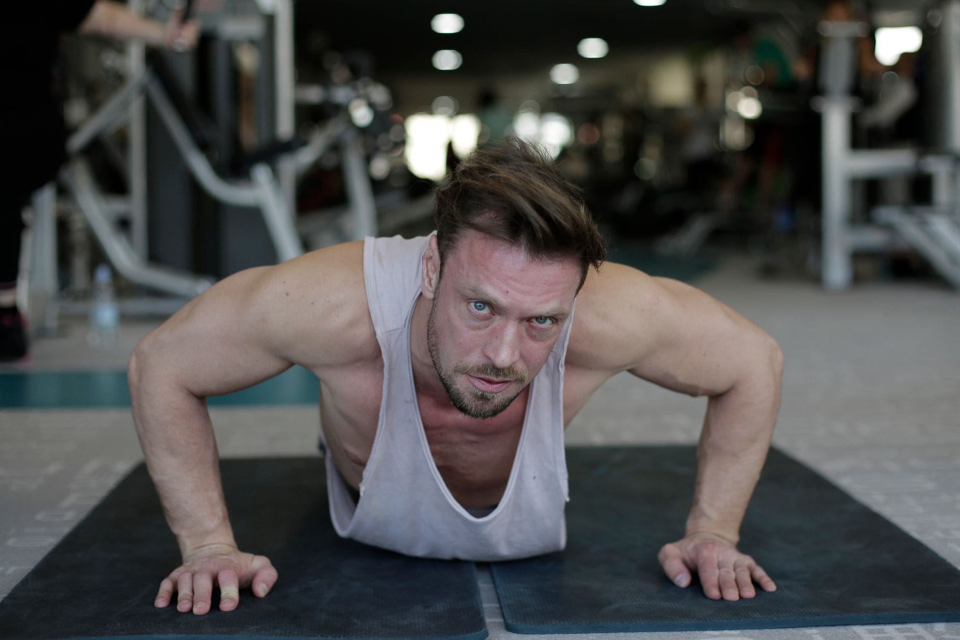Man in plank position lowering into a push-up on a wooden floor