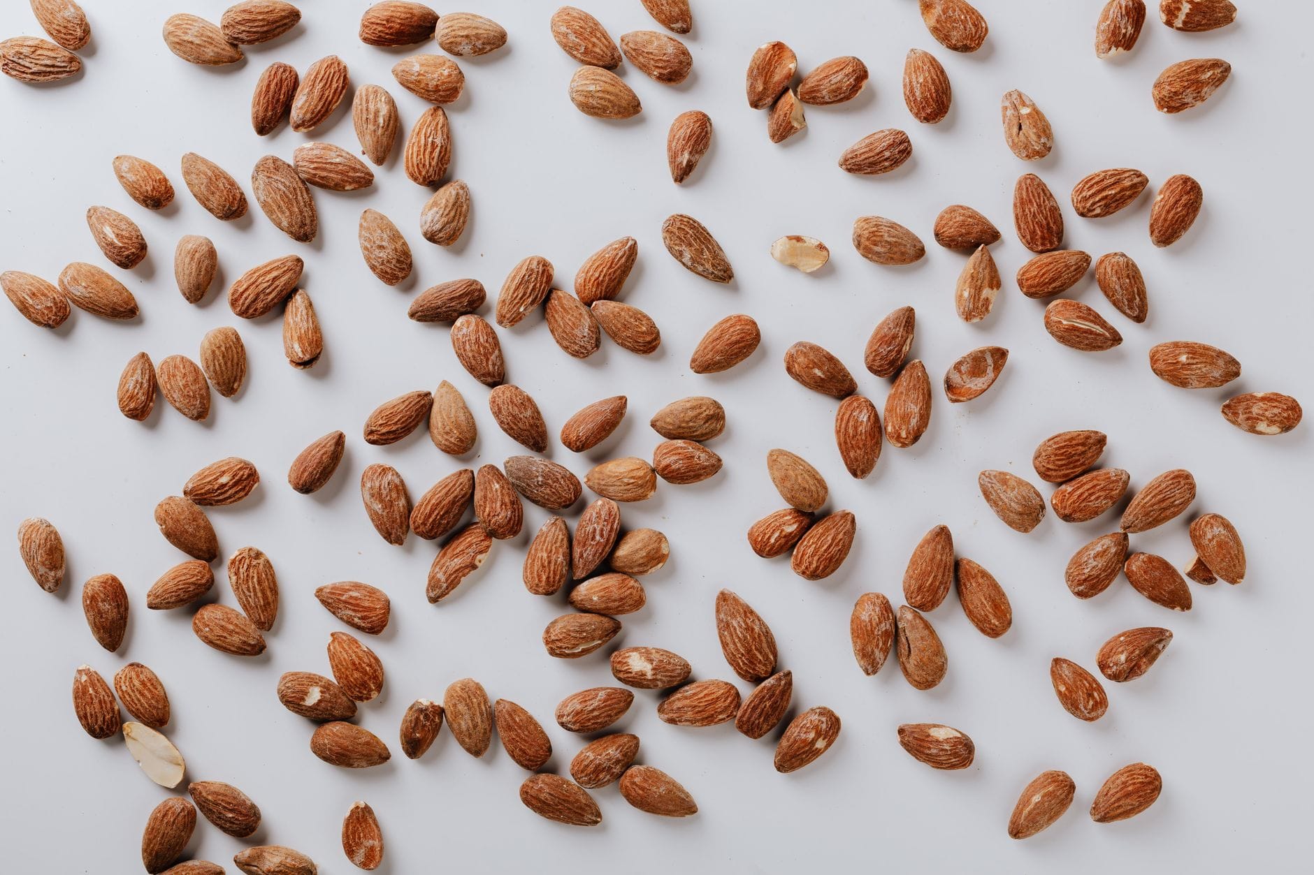 A wooden bowl overflowing with raw almonds and mixed nuts