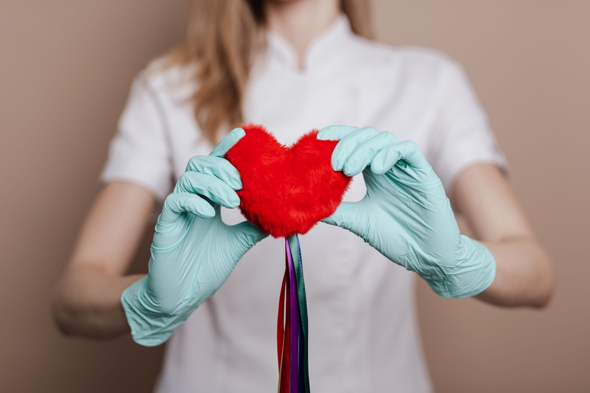 a person in a white coat cradling a small red heart model