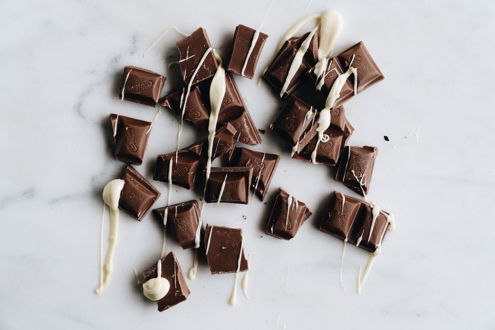 Cream-colored cocoa butter pieces stacked beside dark cocoa beans on wood