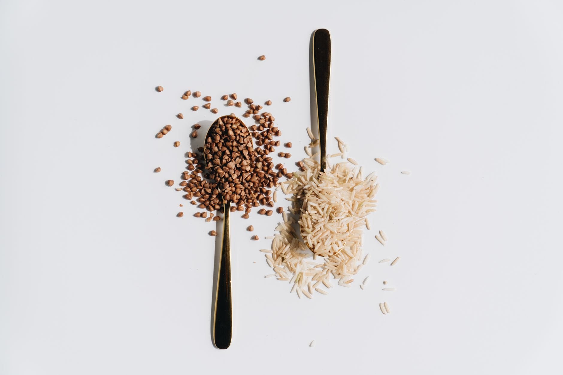 Uncooked light-brown farro grains piled on a wooden spoon