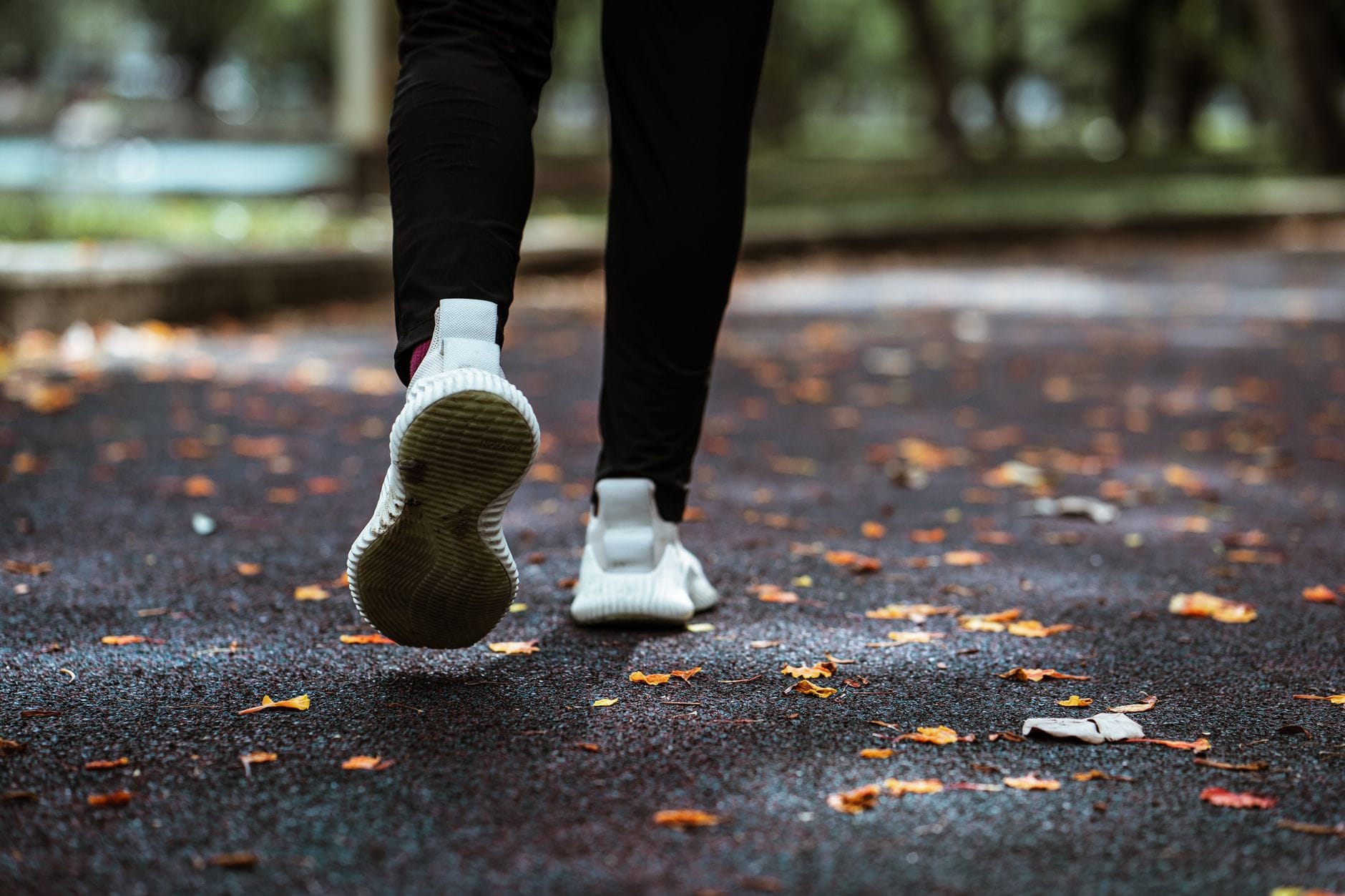 Runner sprinting along a sunny park path in athletic wear