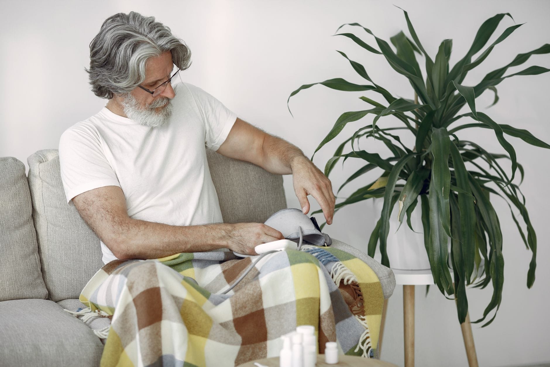 Person pressing a warm heating pad against a sore shoulder at home
