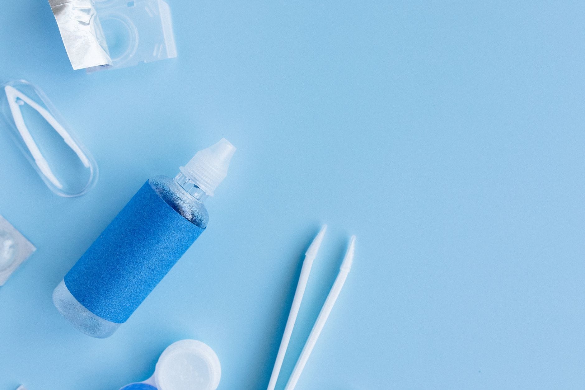 A hand holding a small bottle of lubricating eye drops near the face