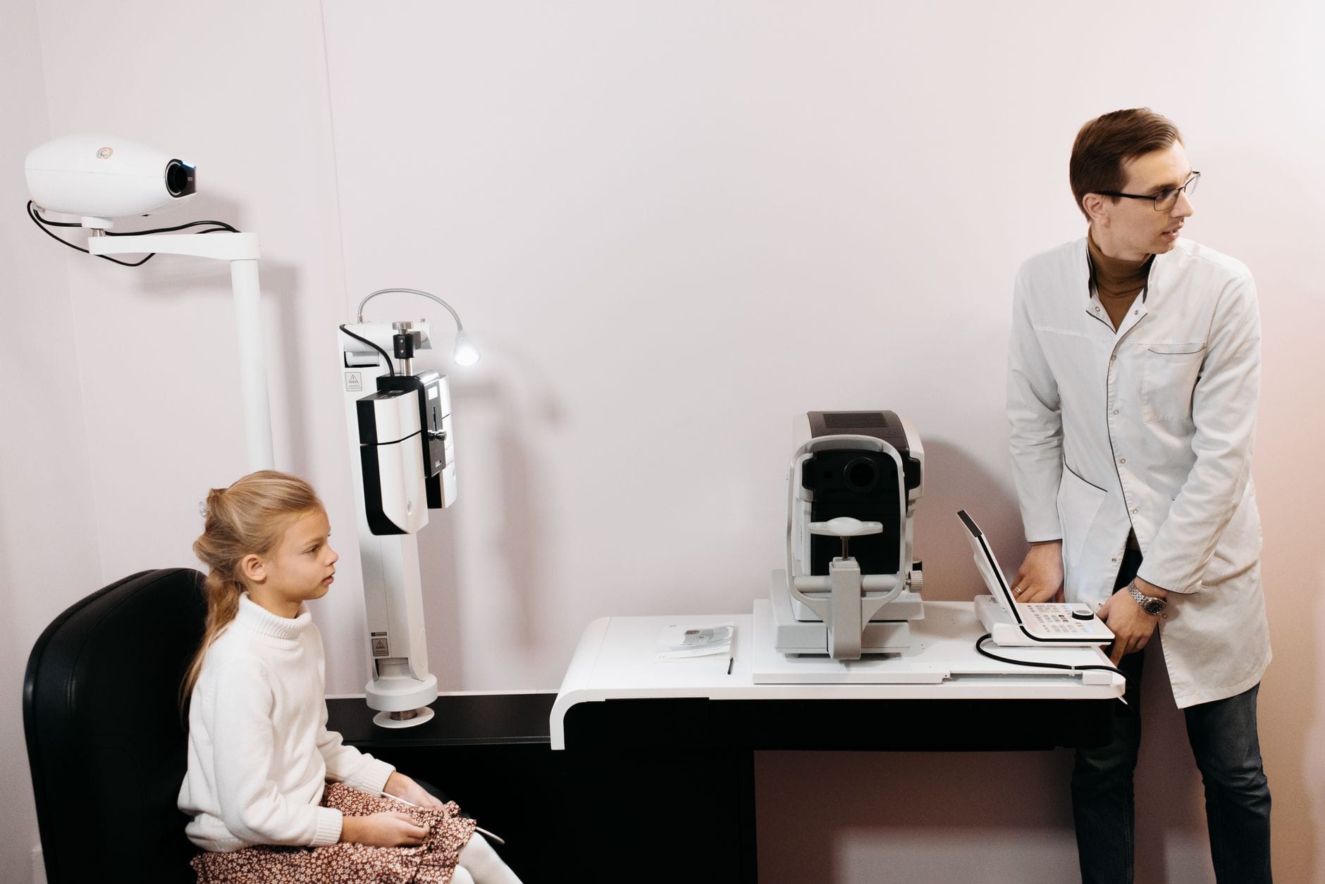 An optometrist examines a woman's eyes through a phoropter in a clinic