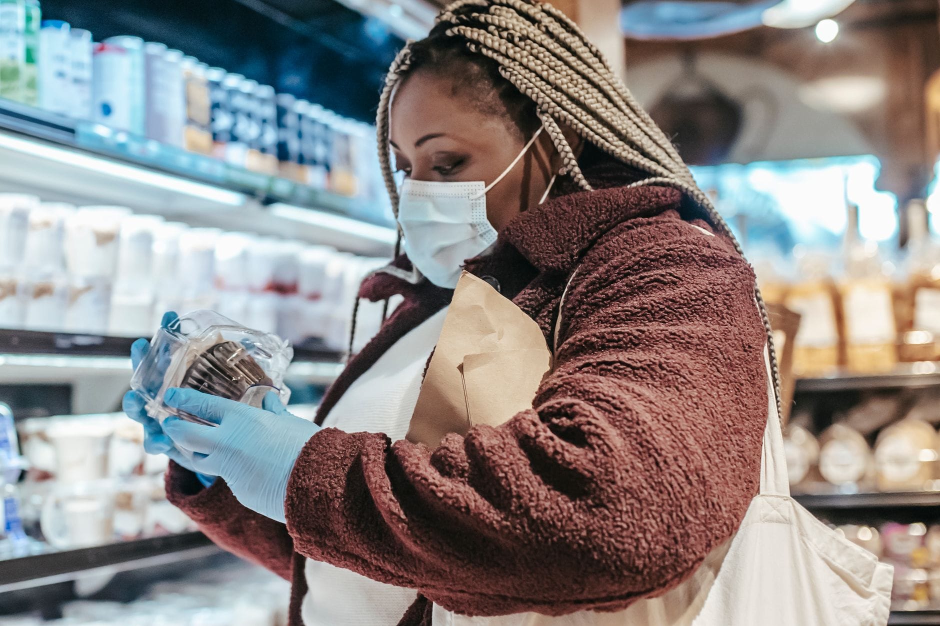 Woman in a grocery aisle studying the label on a package