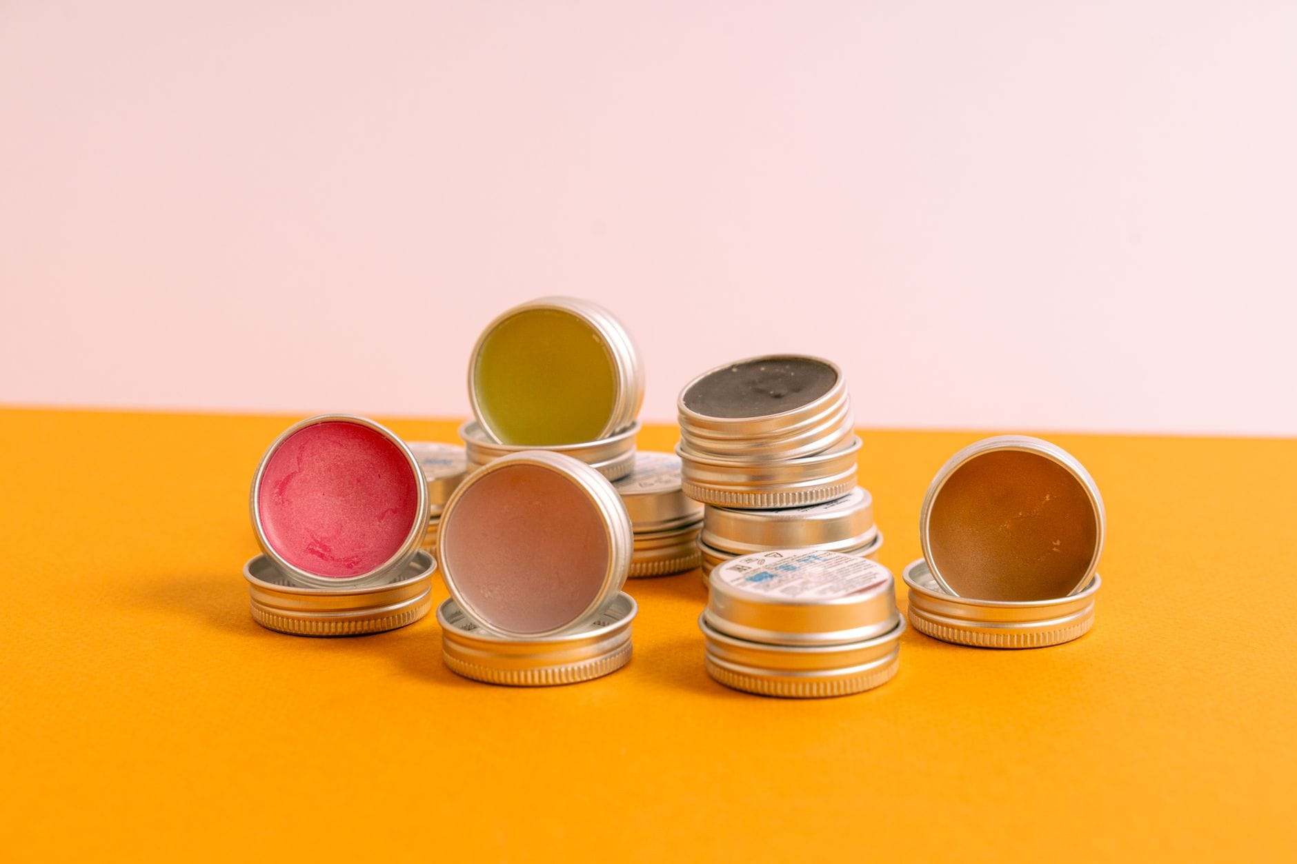 Fingertip smearing dark salve from a small round metal tin