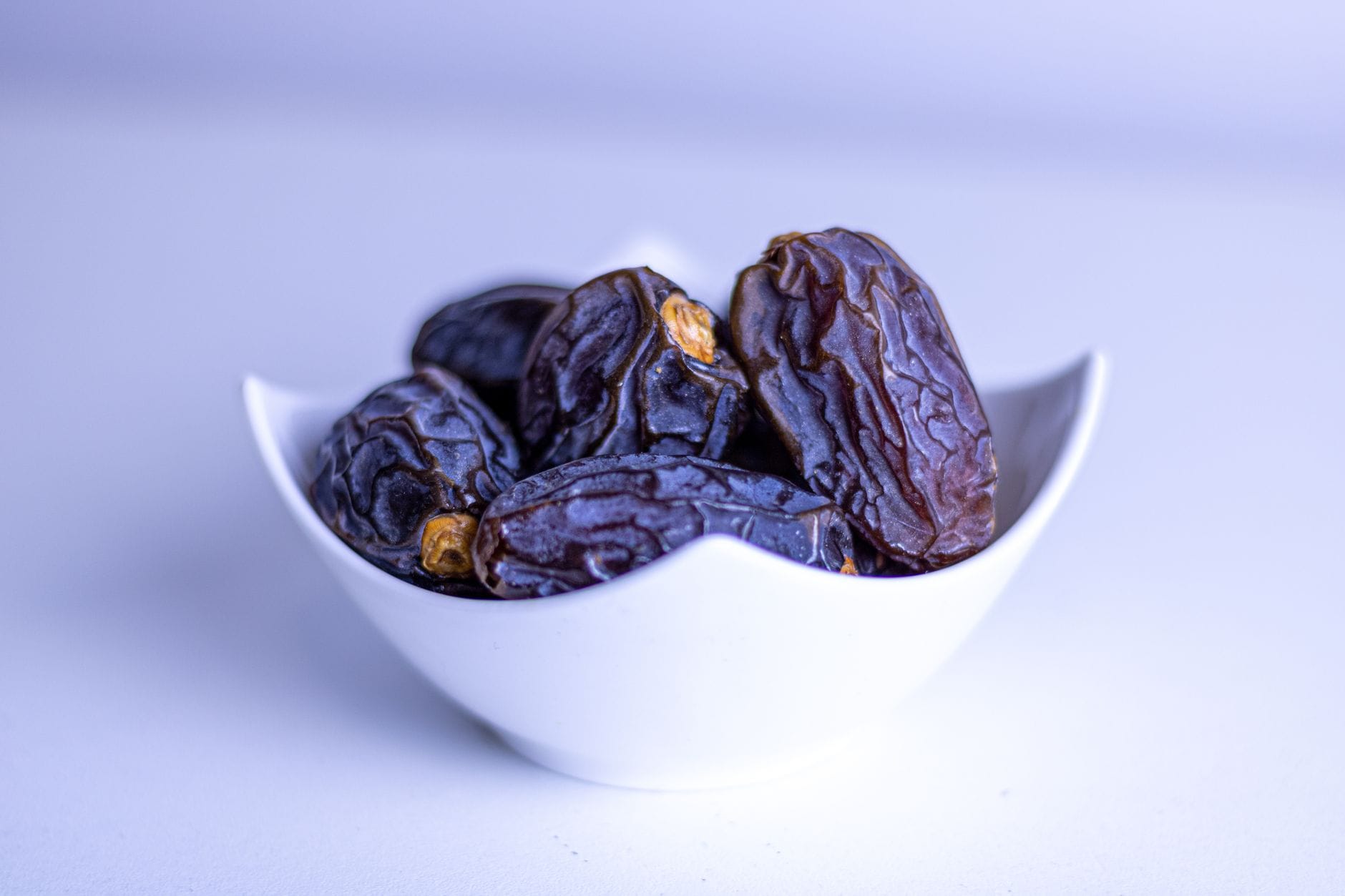 Pile of glossy brown dates heaped in a wooden bowl