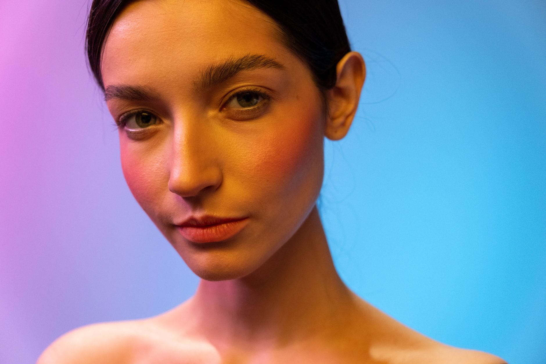 Close-up of a smiling woman with clear, healthy-looking skin in soft light