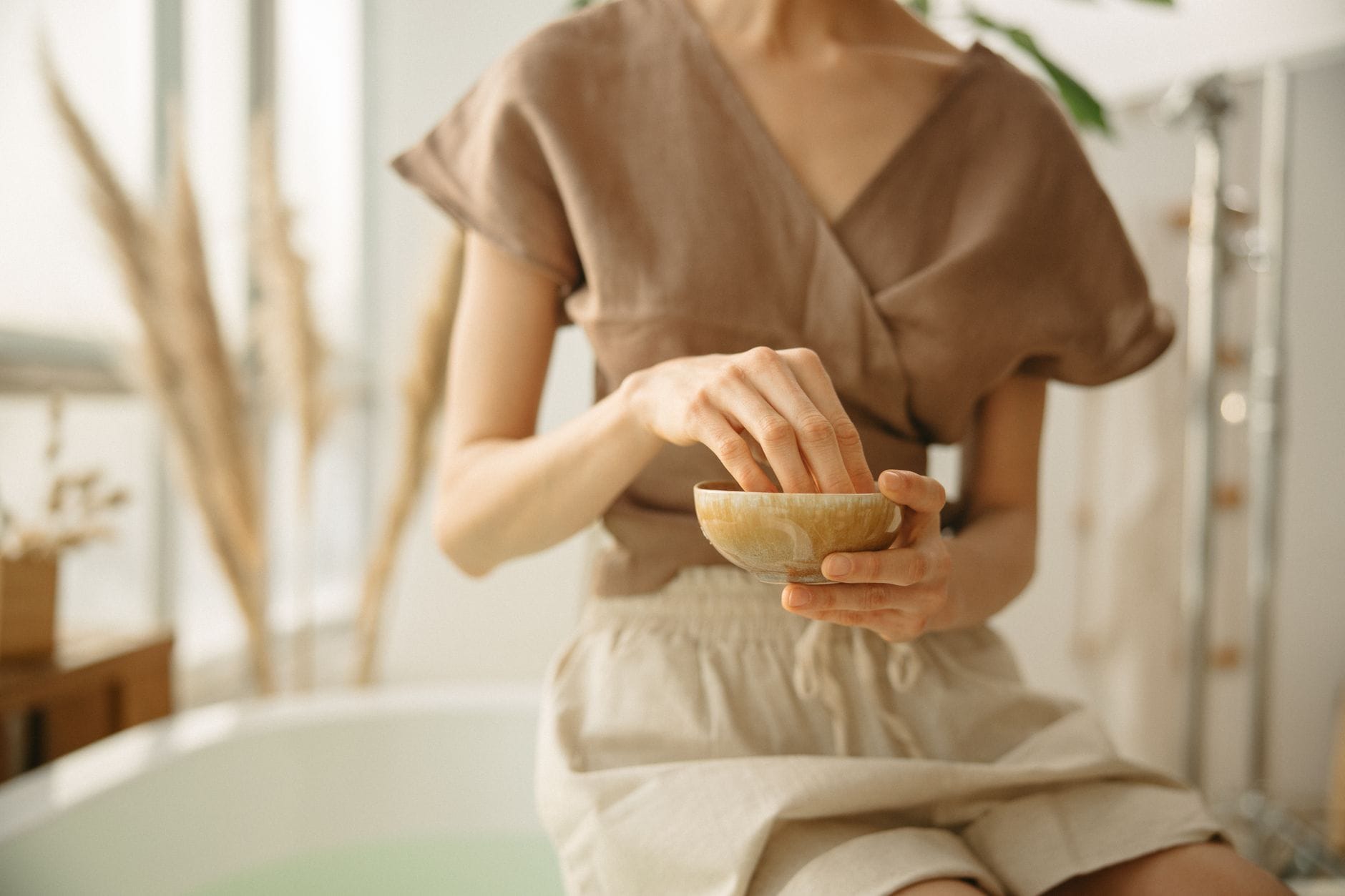 A person leaning over a bowl of steaming water with a towel draped over the head