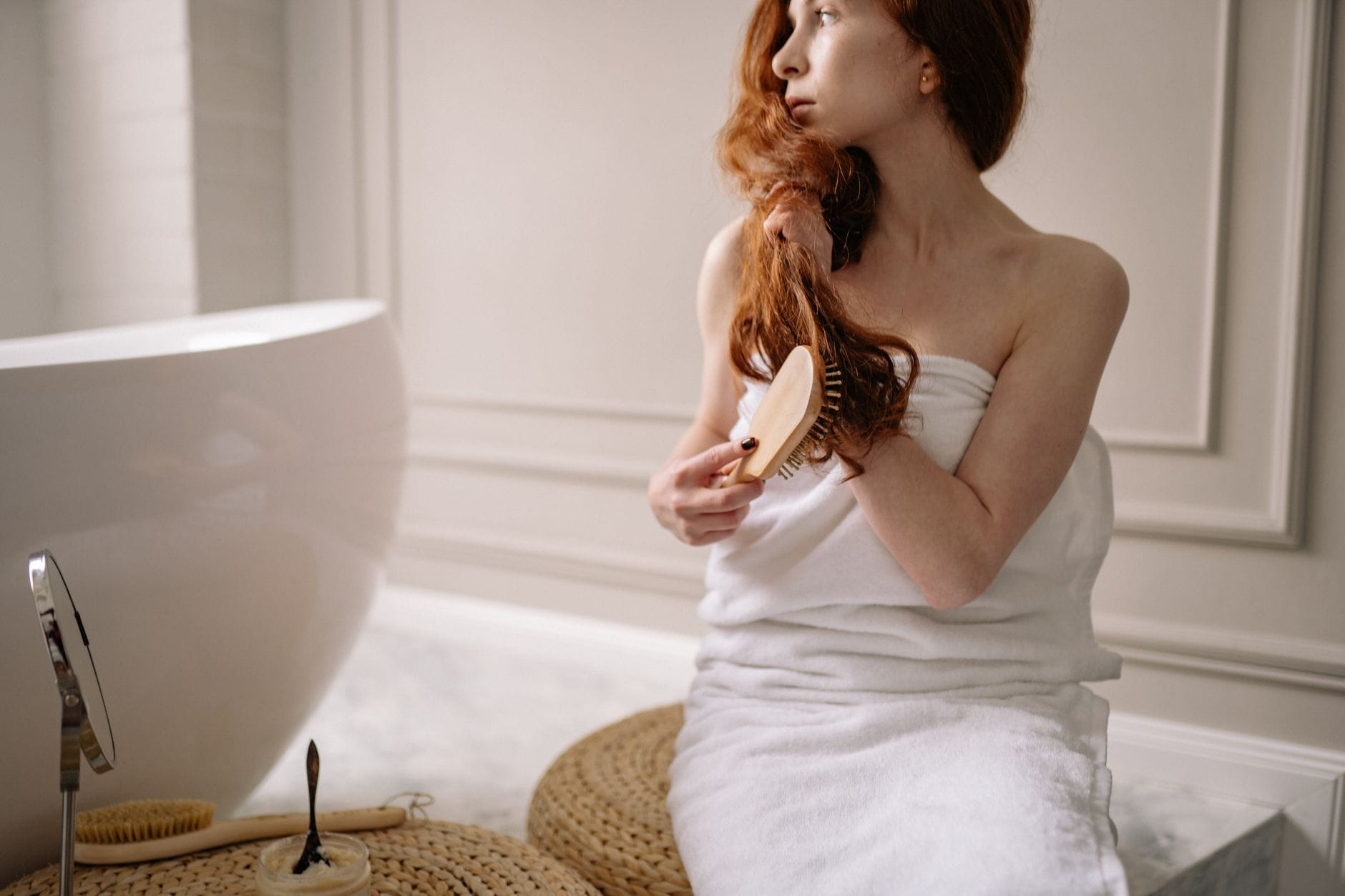 A woman running a wide brush through long, shiny brown hair