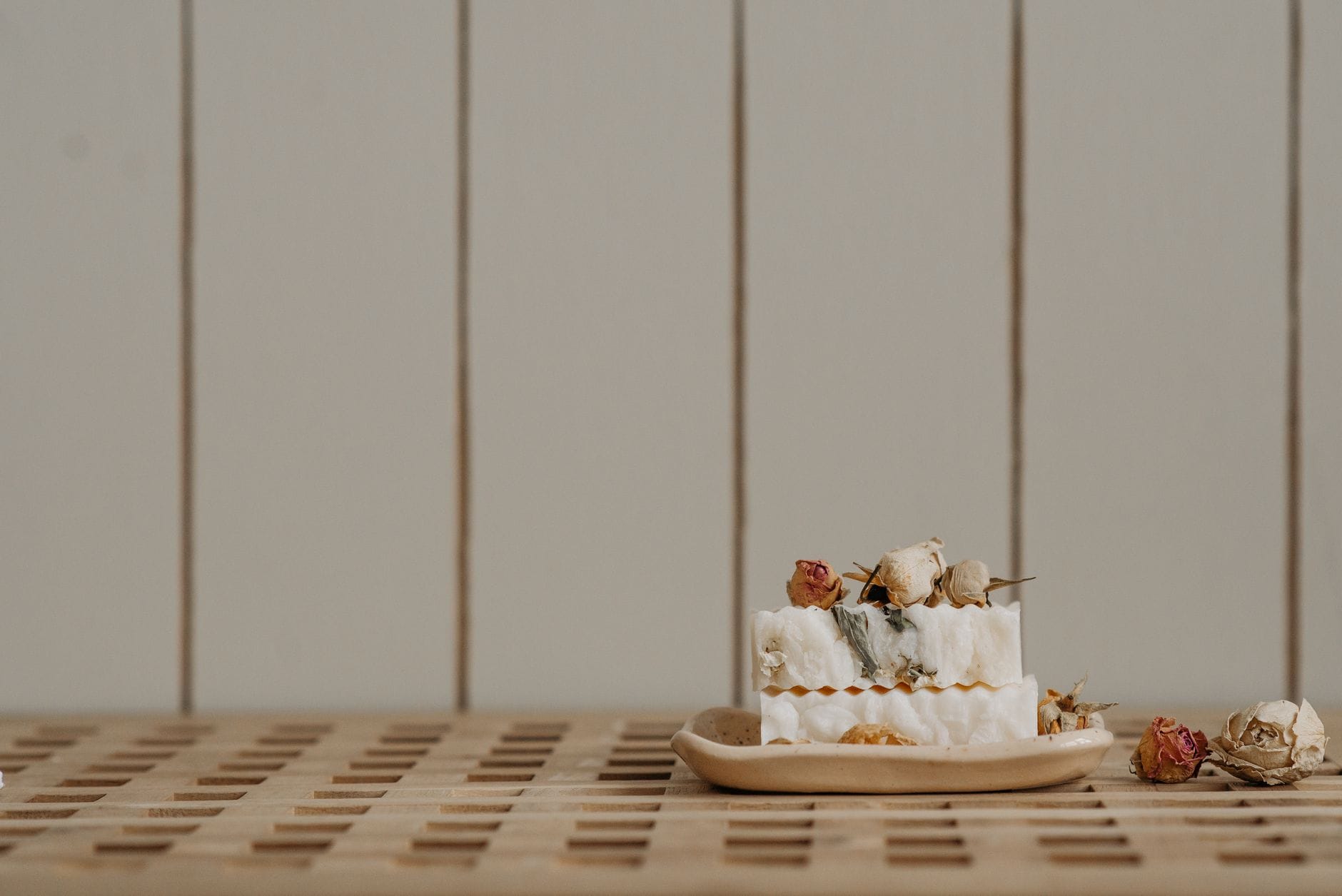 A plain white bar of soap resting in a ceramic dish by a sink