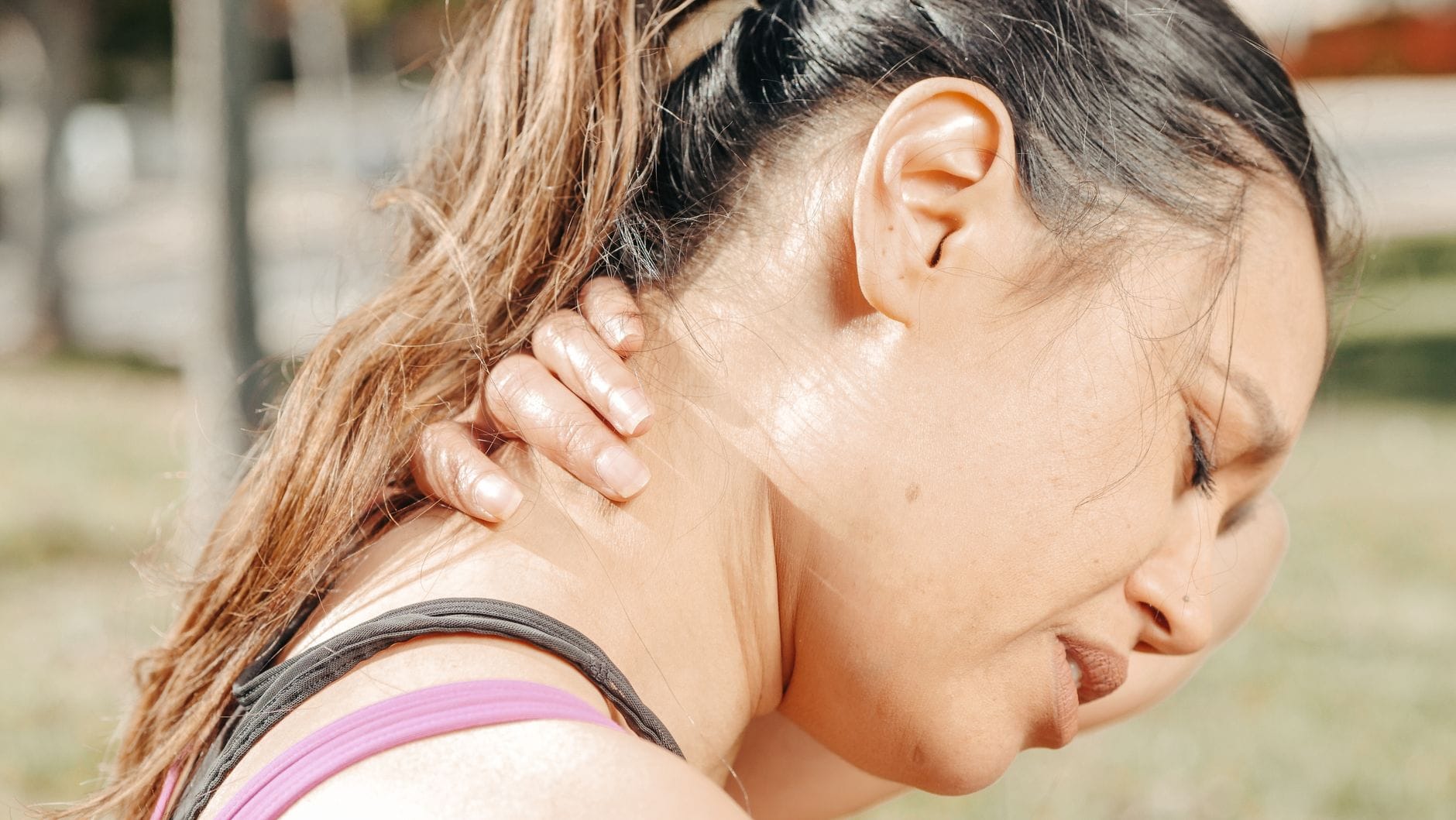 A person pressing their fingers into a tense, aching neck